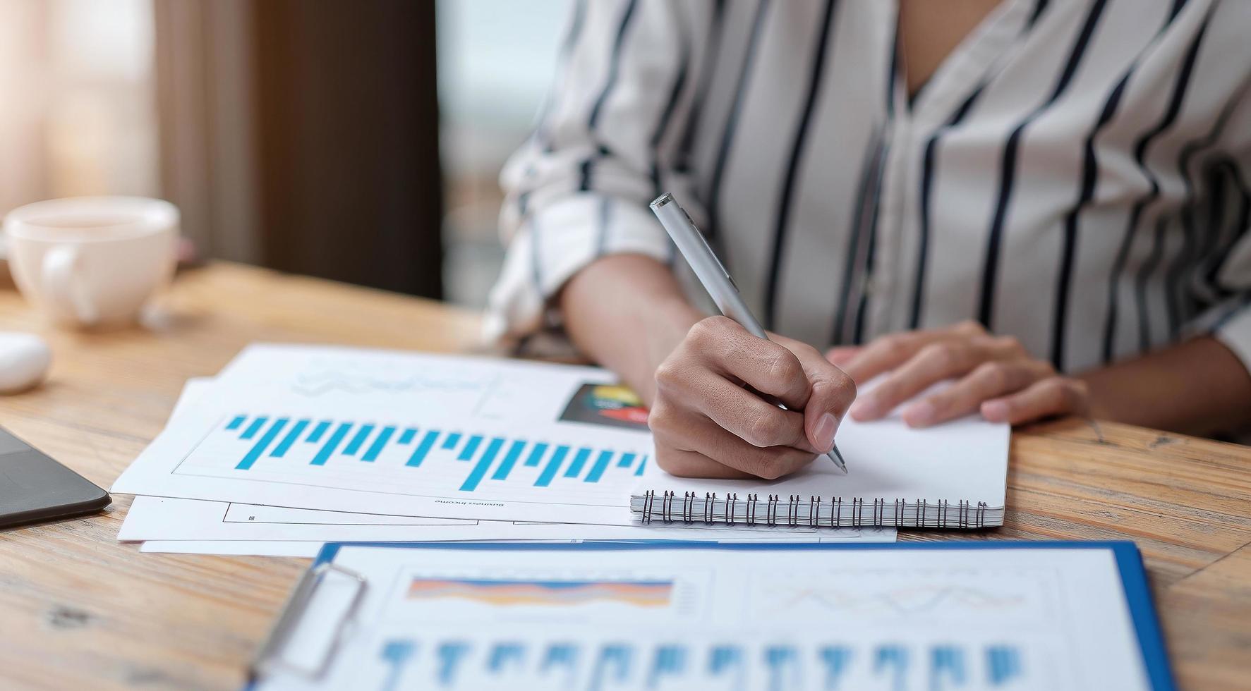 manos del gerente de mujeres de negocios financieros tomando notas foto