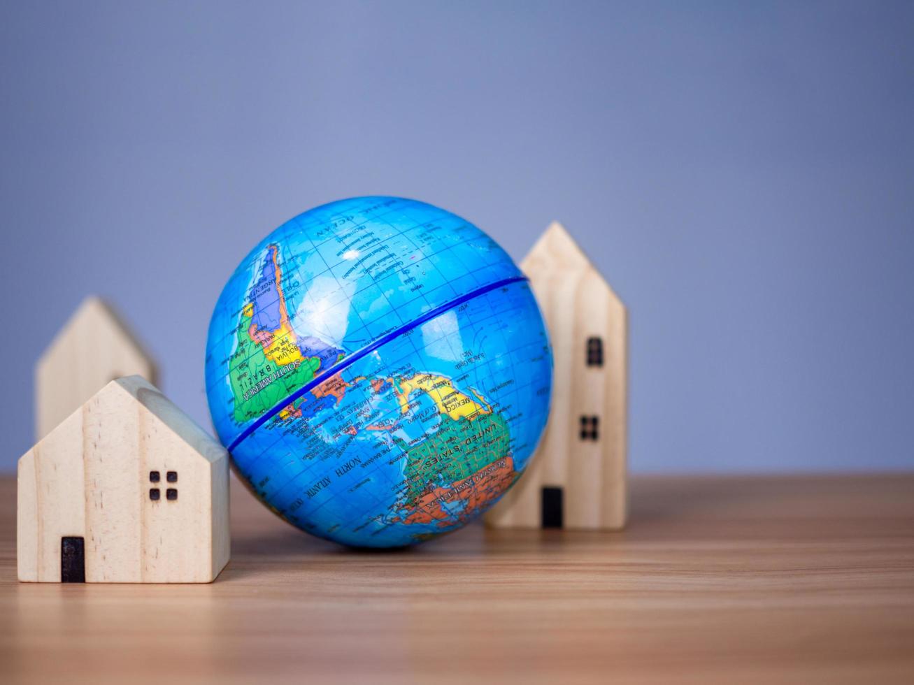 A wooden model house is placed beside a replica globe. photo