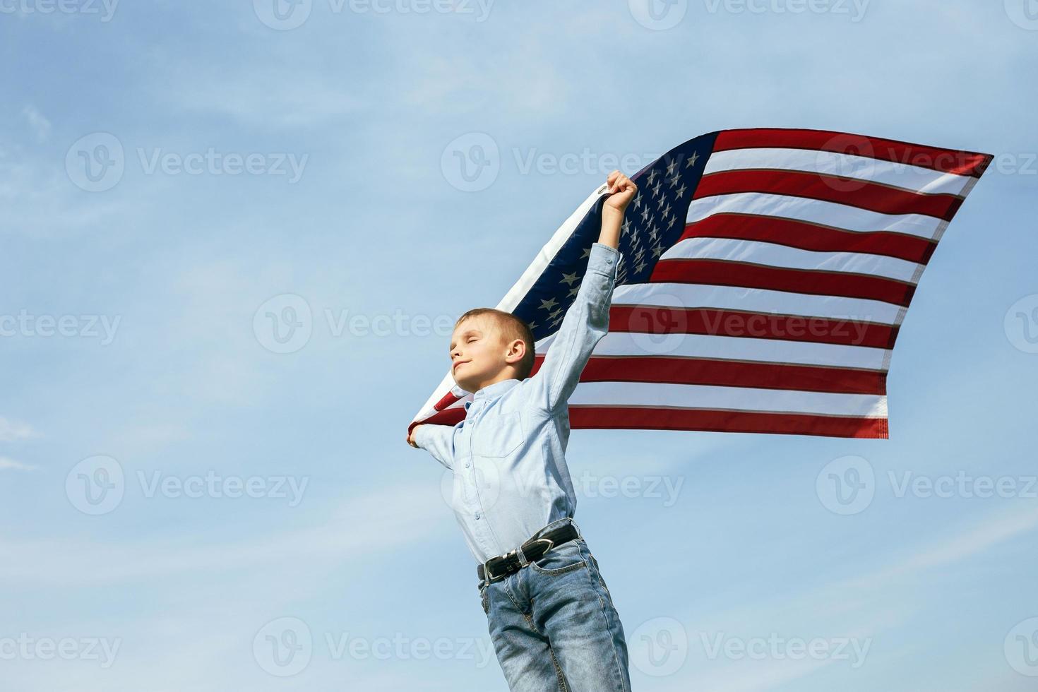 un niño sostiene una bandera de los estados unidos contra el cielo foto