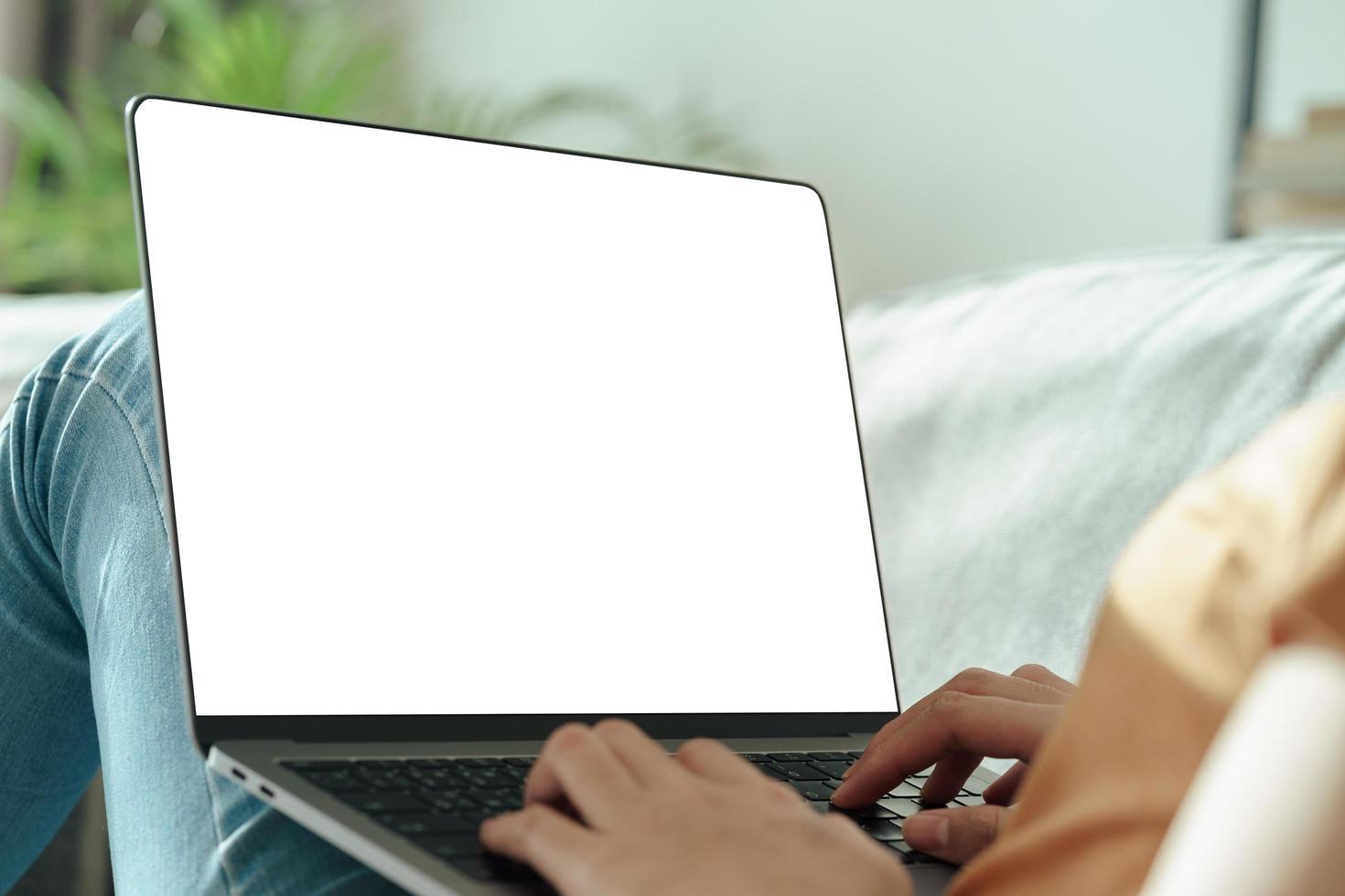Woman typing laptop keyboard with white blank screen on the sofa. photo