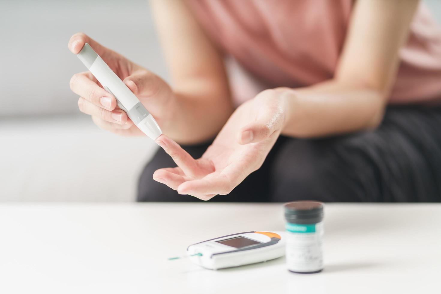 Woman use lancet on finger checking blood sugar level by Glucose meter photo