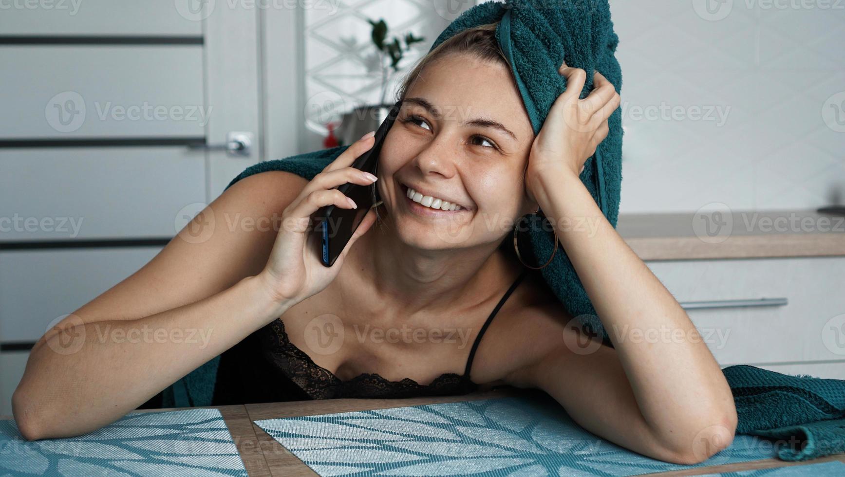 mujer joven en la cocina. hablar por teléfono y sonreír foto