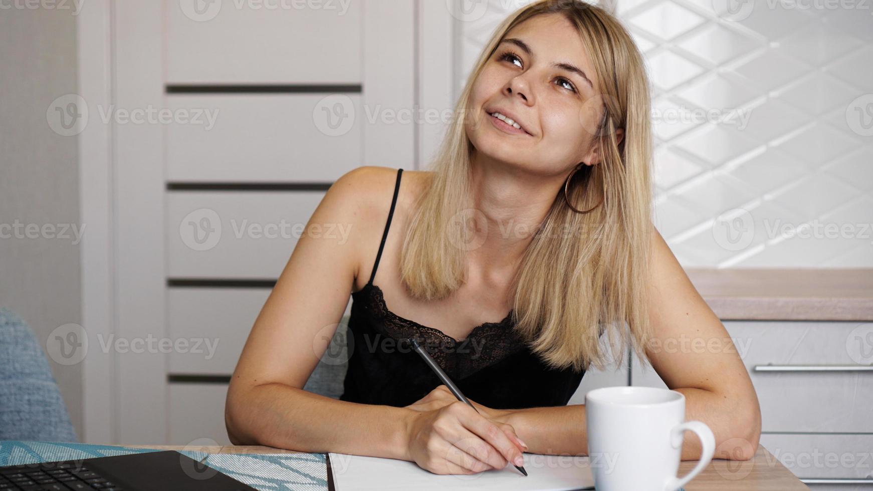 una mujer se sienta en la cocina y escribe una carta o sus deseos foto