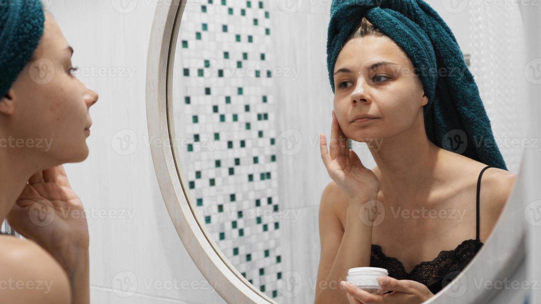 Una foto de una mujer hermosa joven que se aplica loción en la cara