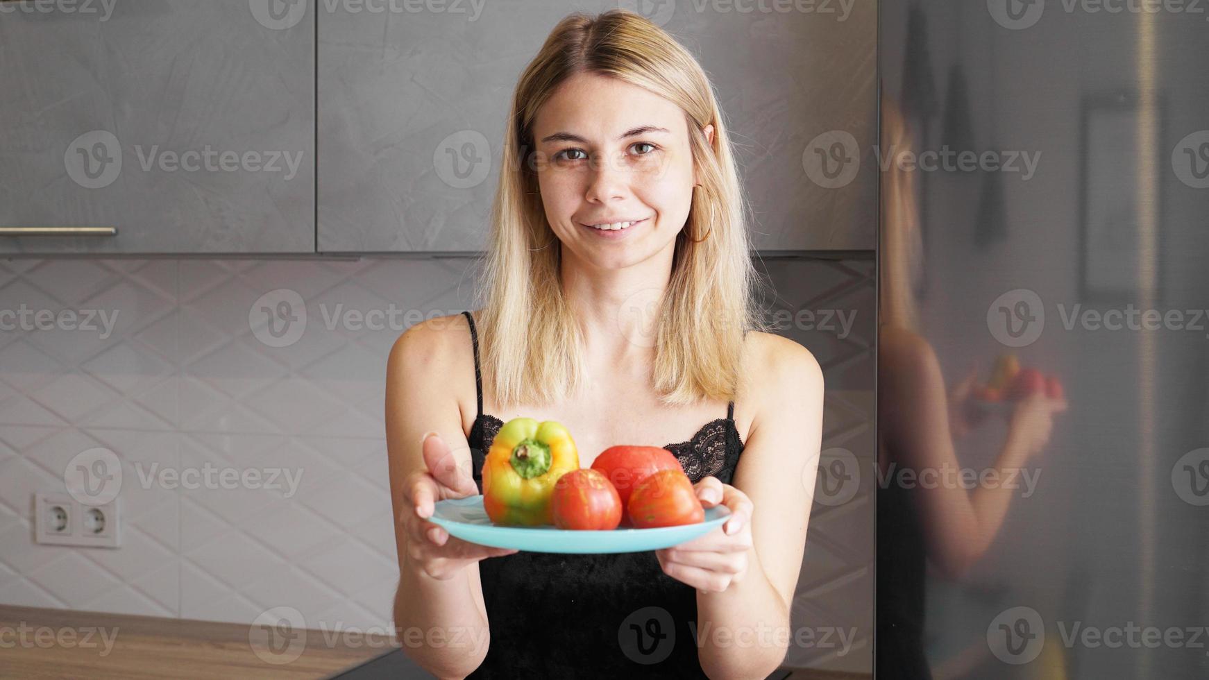 Woman holding plate with fresh vegetables and smiling photo