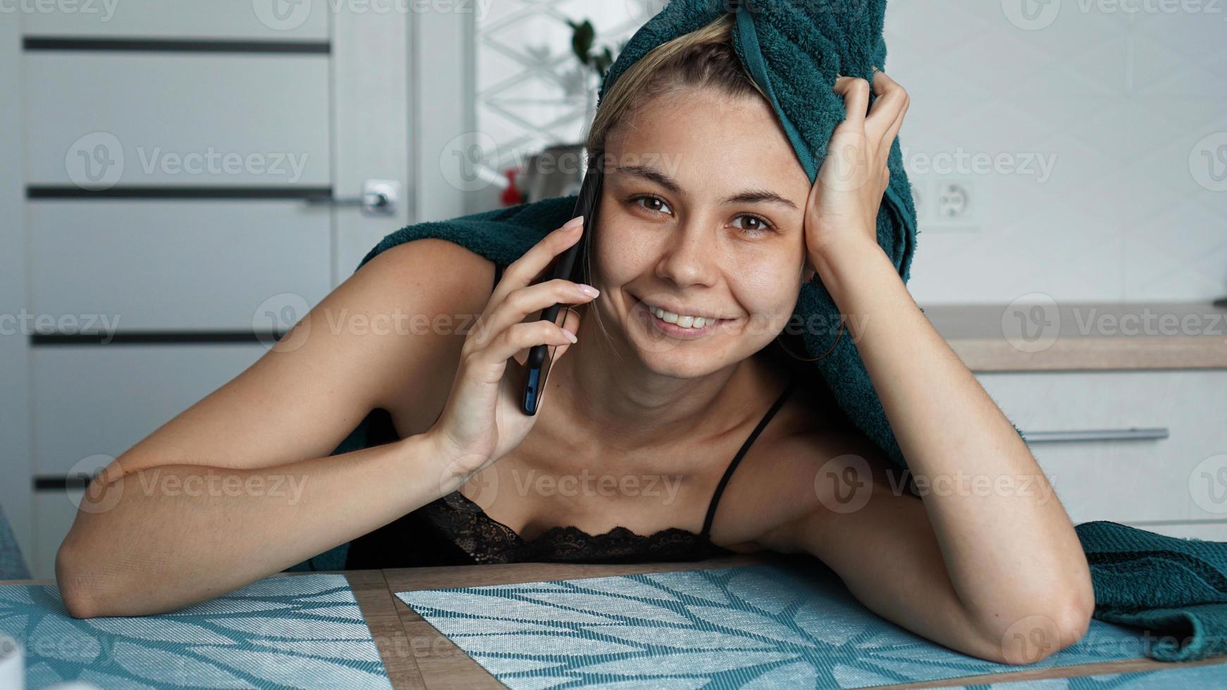 Young woman in kitchen. Talking on phone and smile photo