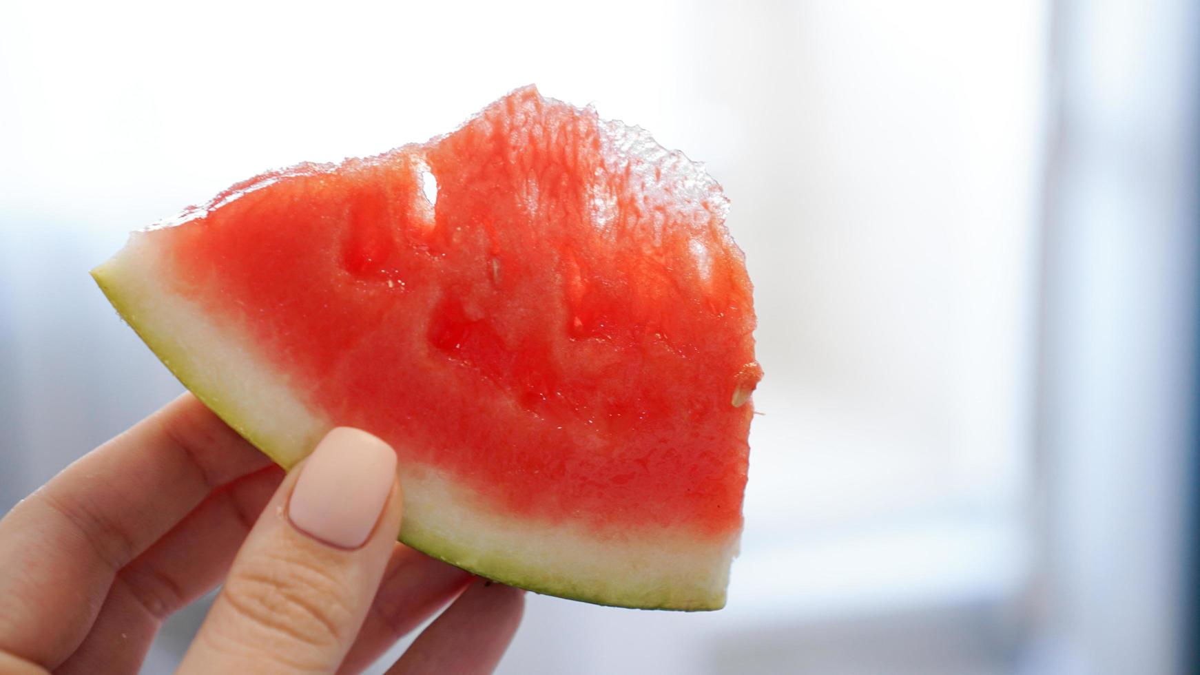 Slice of watermelon in hand on a blurred background photo