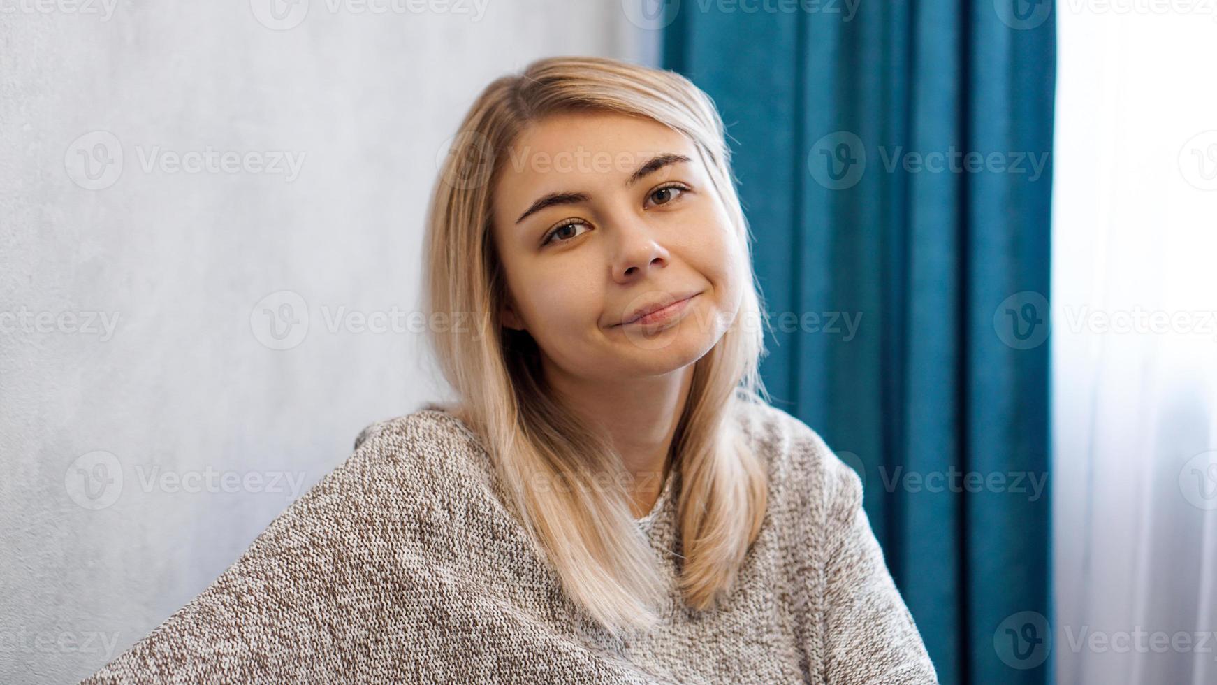 mujer feliz en suéter mirando a la cámara con una sonrisa foto