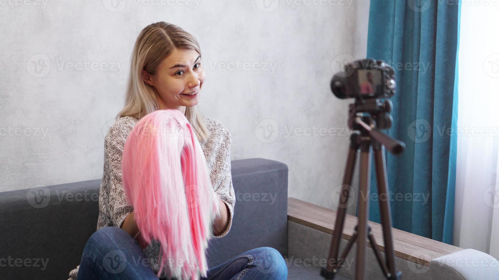 Woman blogger records video. She shows pink wig photo