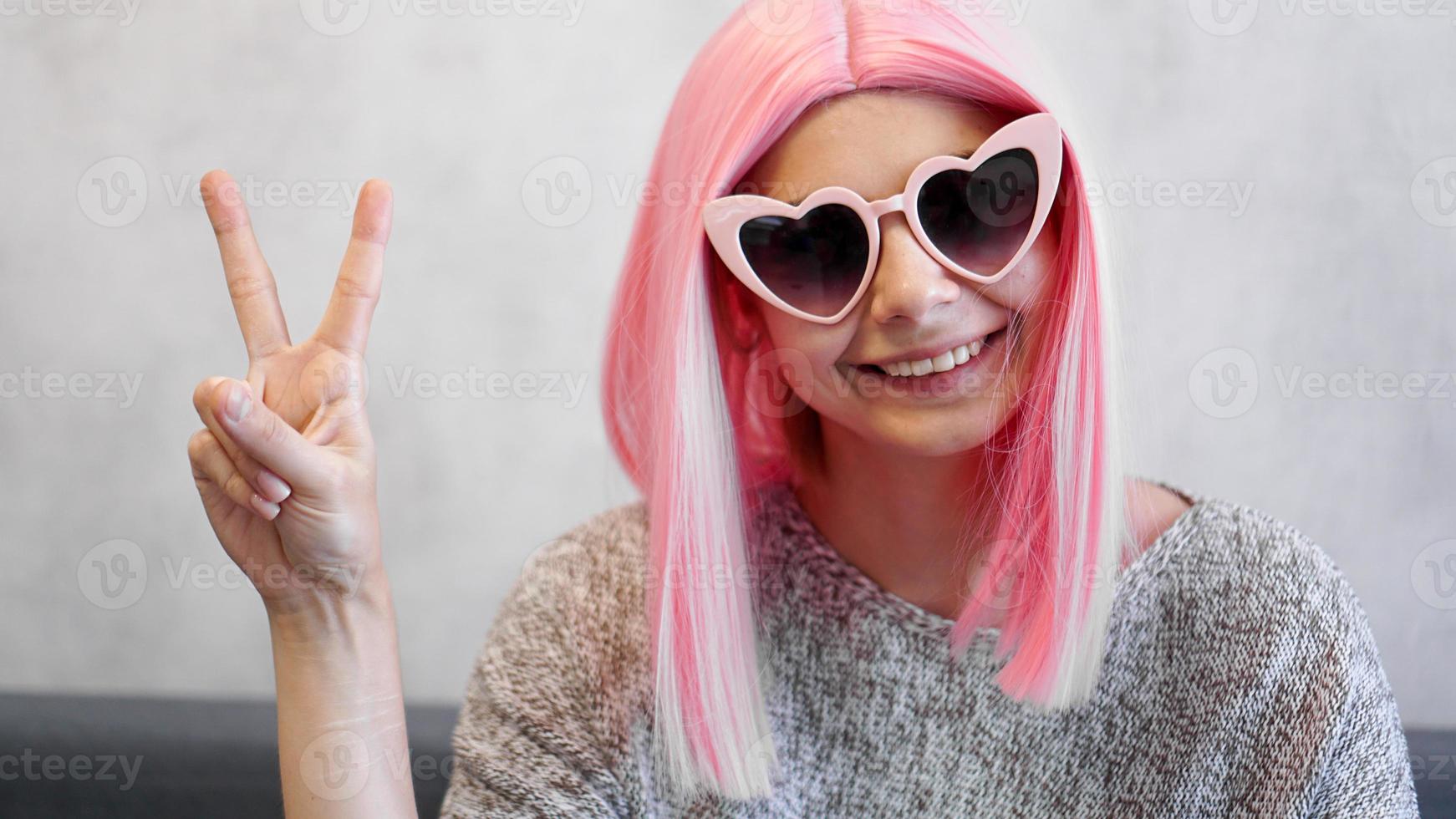 Retrato de una niña alegre feliz mostrando gesto de paz foto