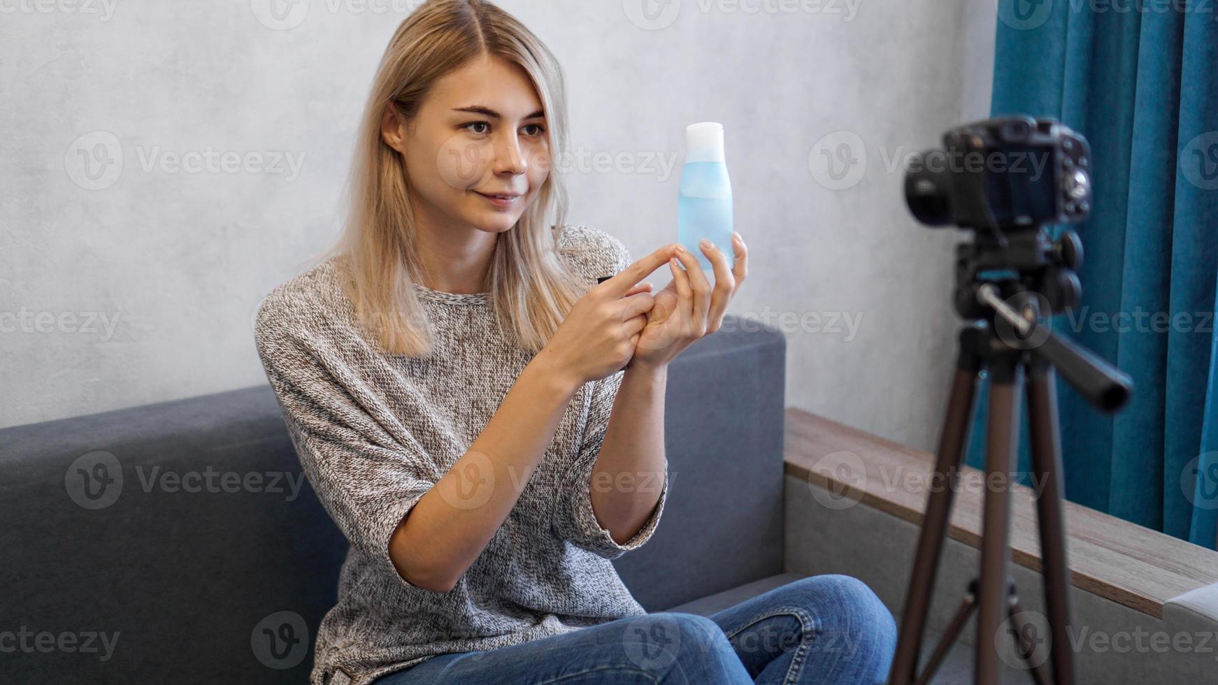 Blogger shows lotion for skin. Cheerful female blogger recording video photo