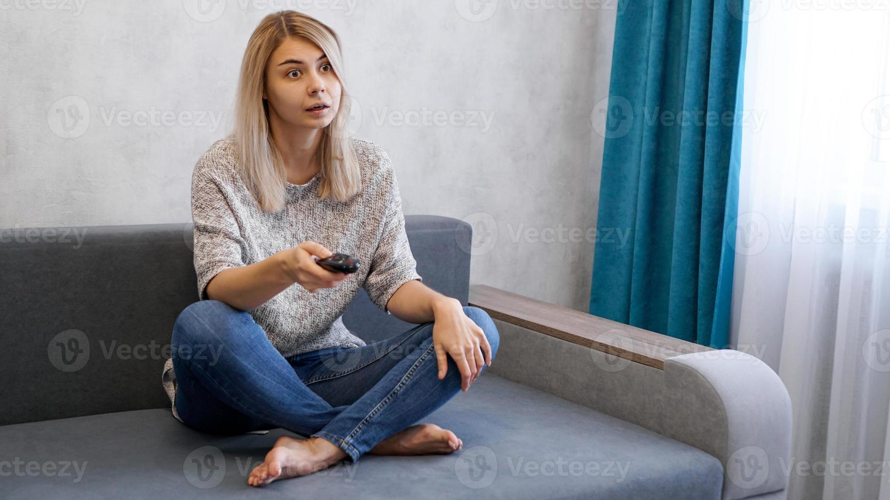 Young beautiful woman watching TV on couch photo