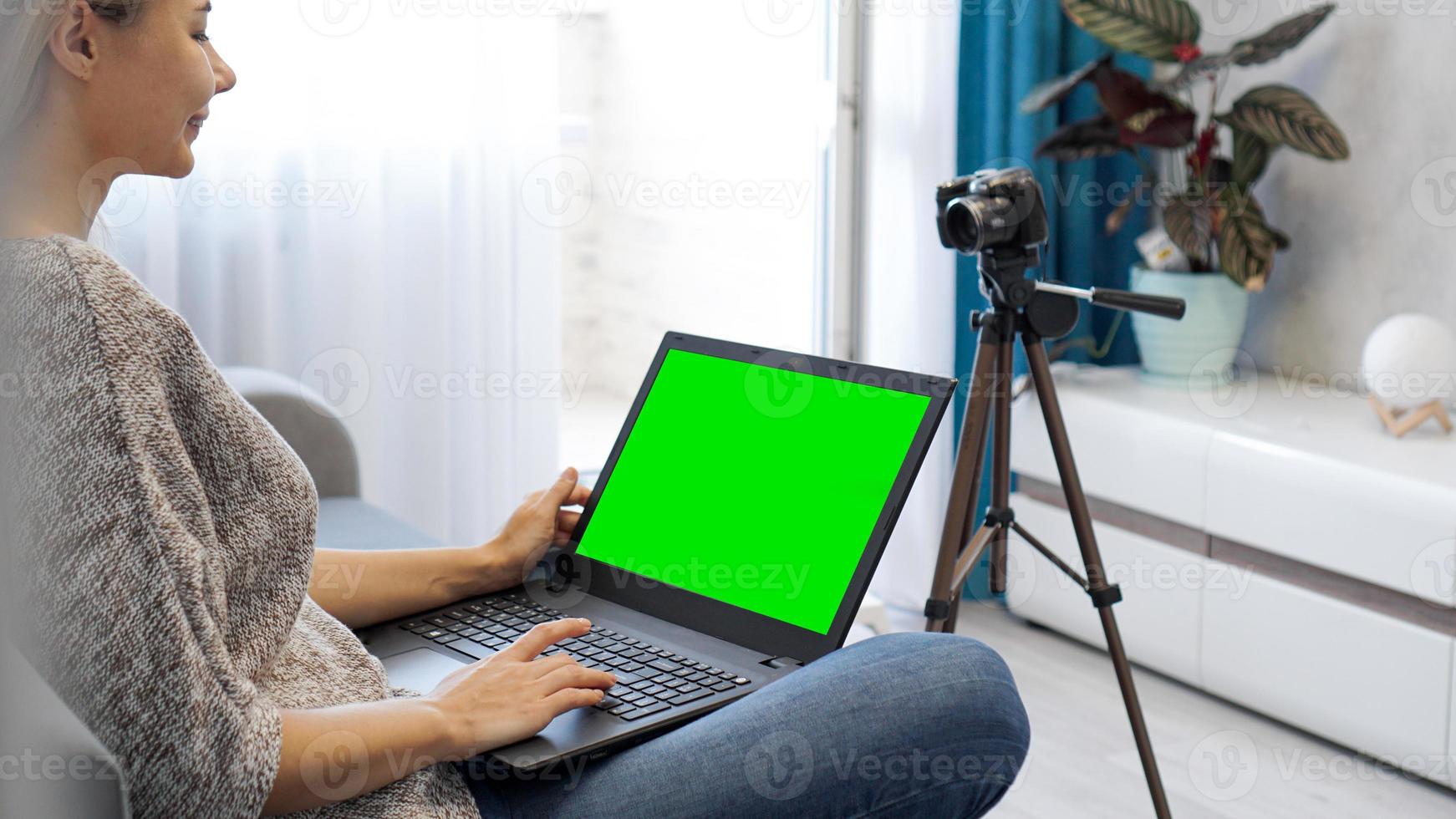View of camera on tripod and laptop with green screen chromakey photo