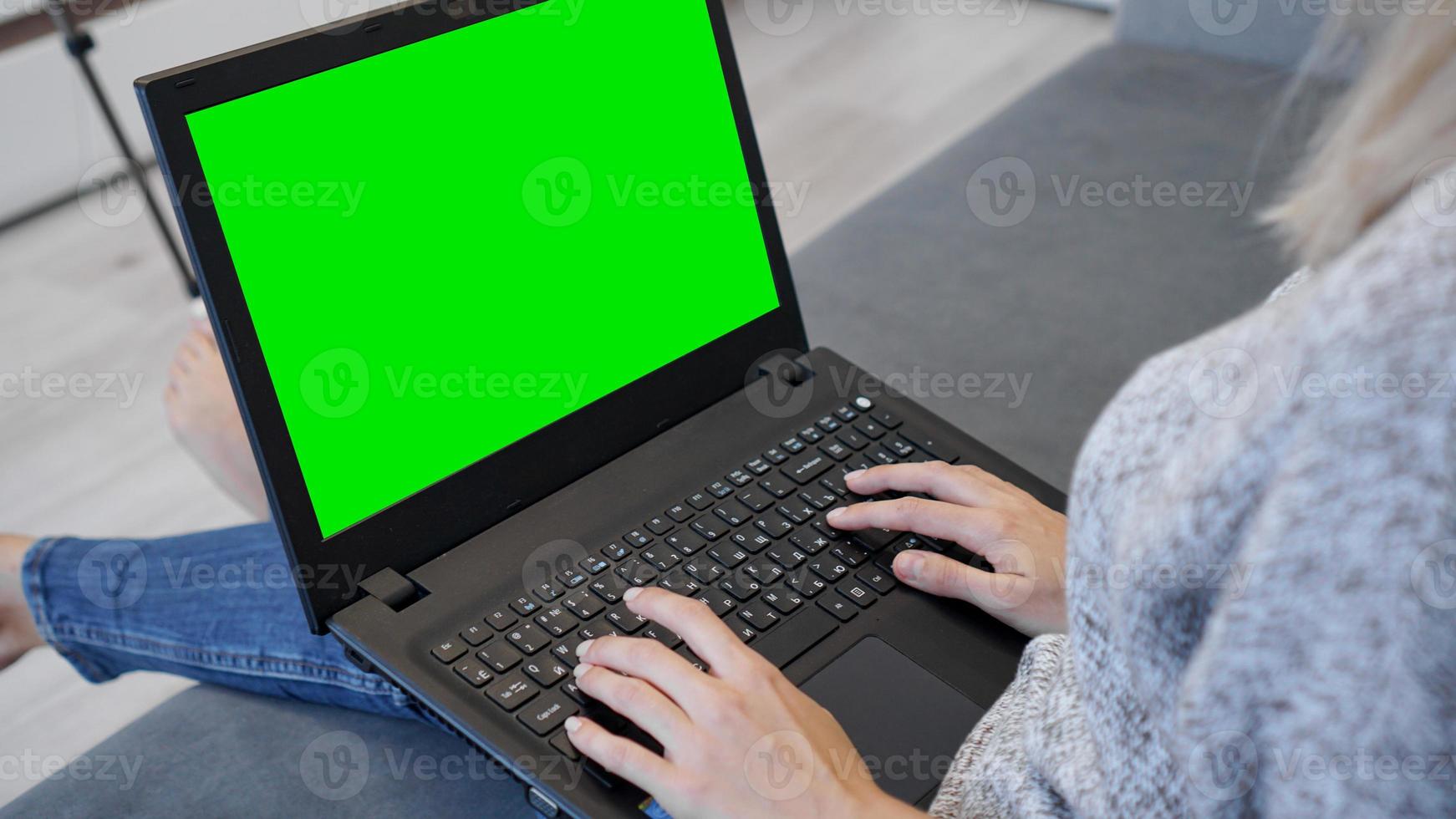 mujer usando laptop con pantalla verde. mujer escribiendo foto