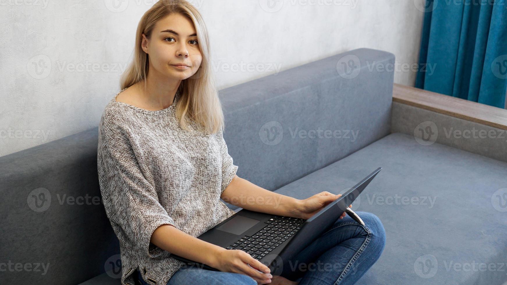 Casual young woman using laptop in living room photo