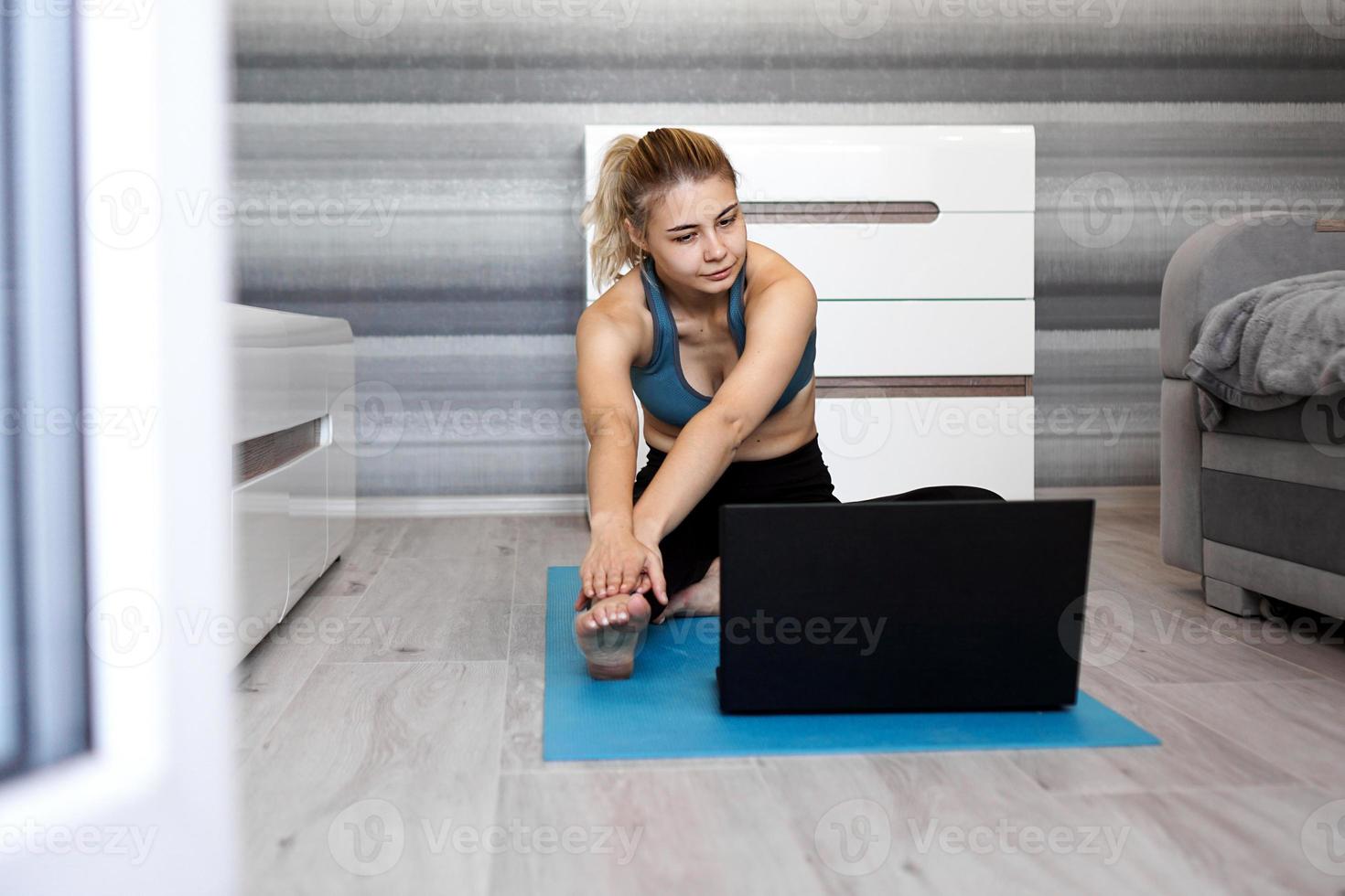 Woman in sportswear watching online video on laptop photo