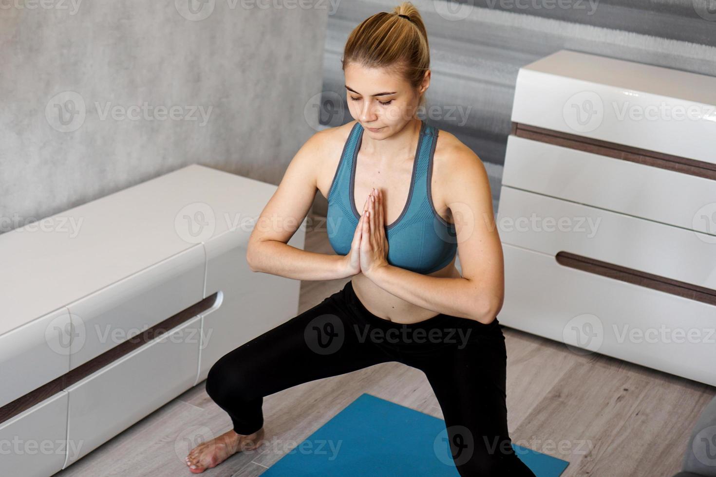 Young woman exercising and doing squats at home photo