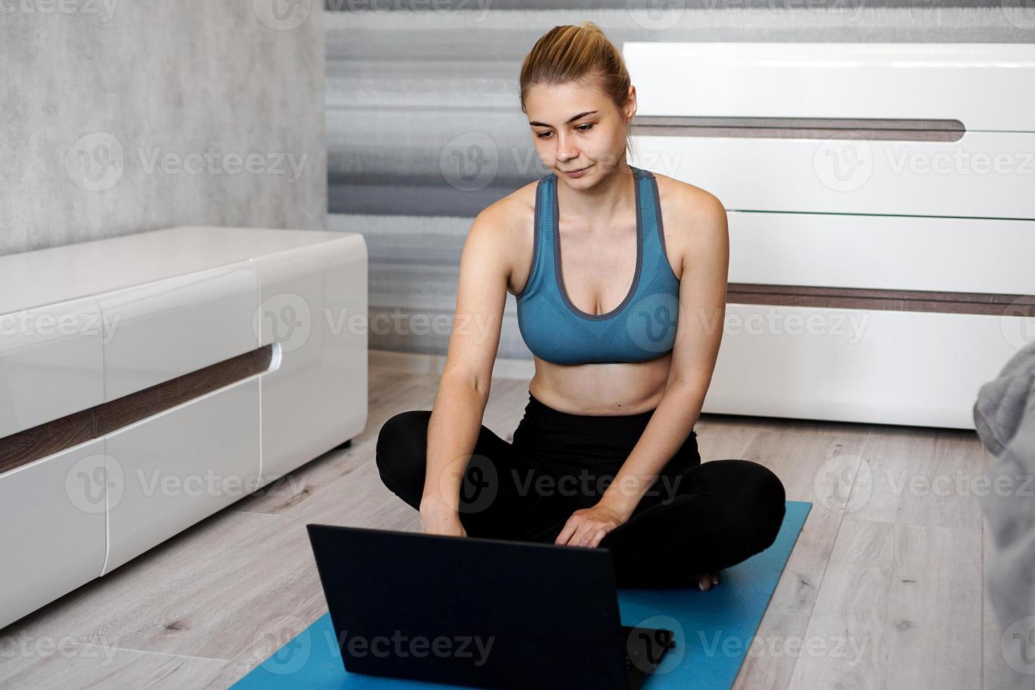 Girl training at home and watching videos on laptop, training photo
