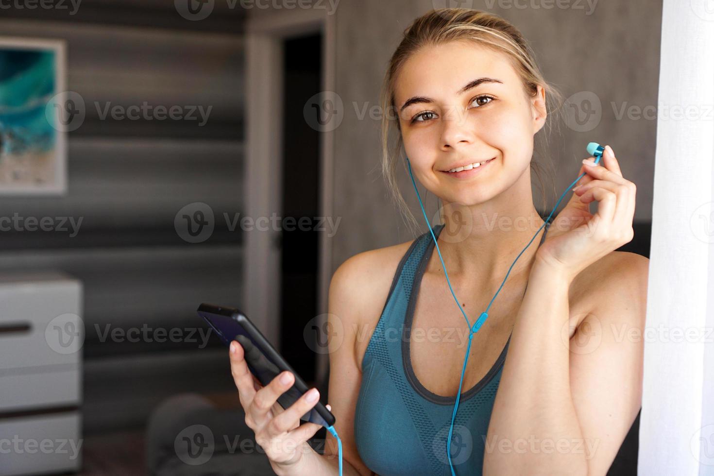 Young pretty sporty girl at home listens to music on headphones photo