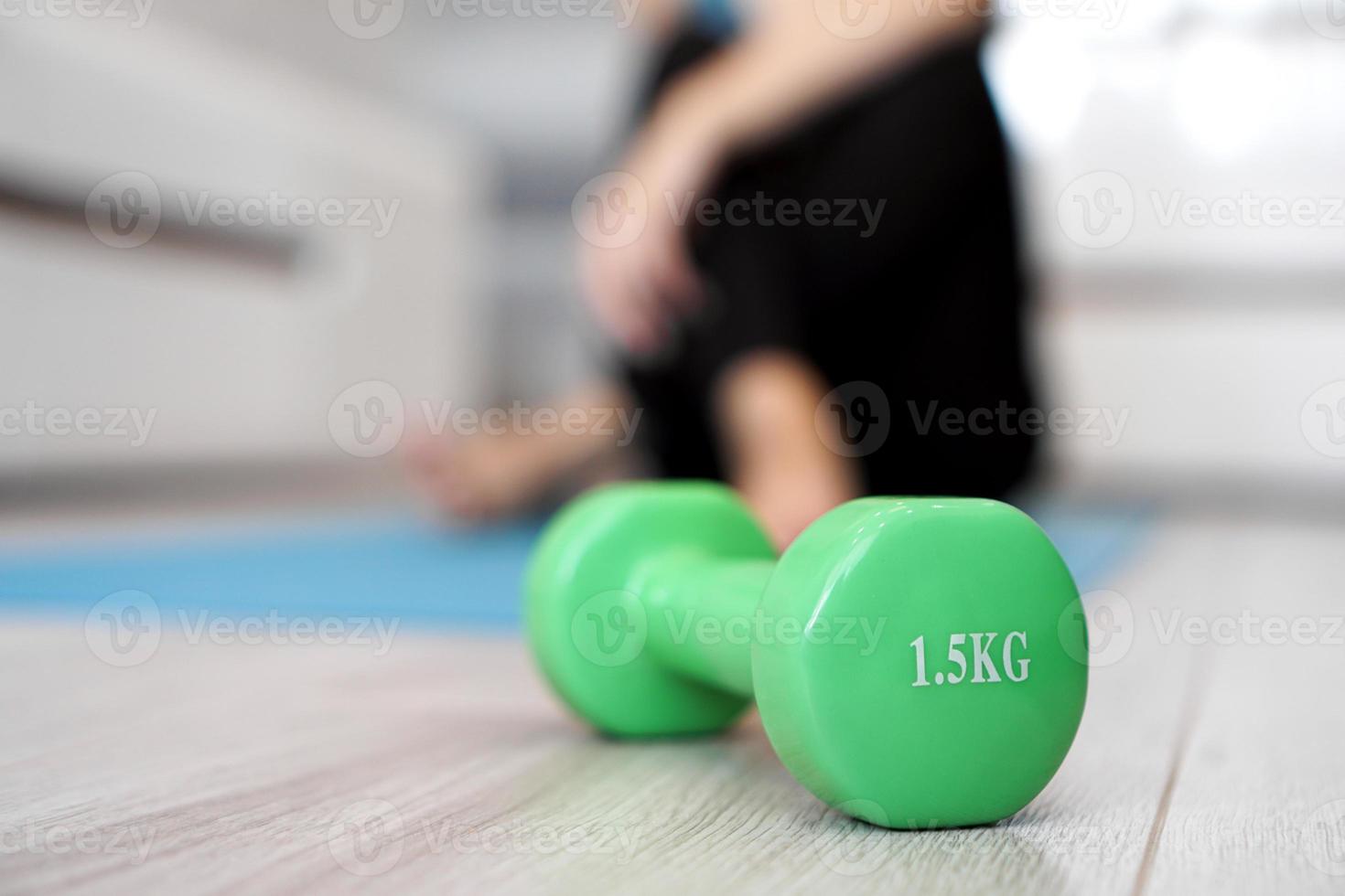 Close up of dumbbell and woman stretching in blurred background photo