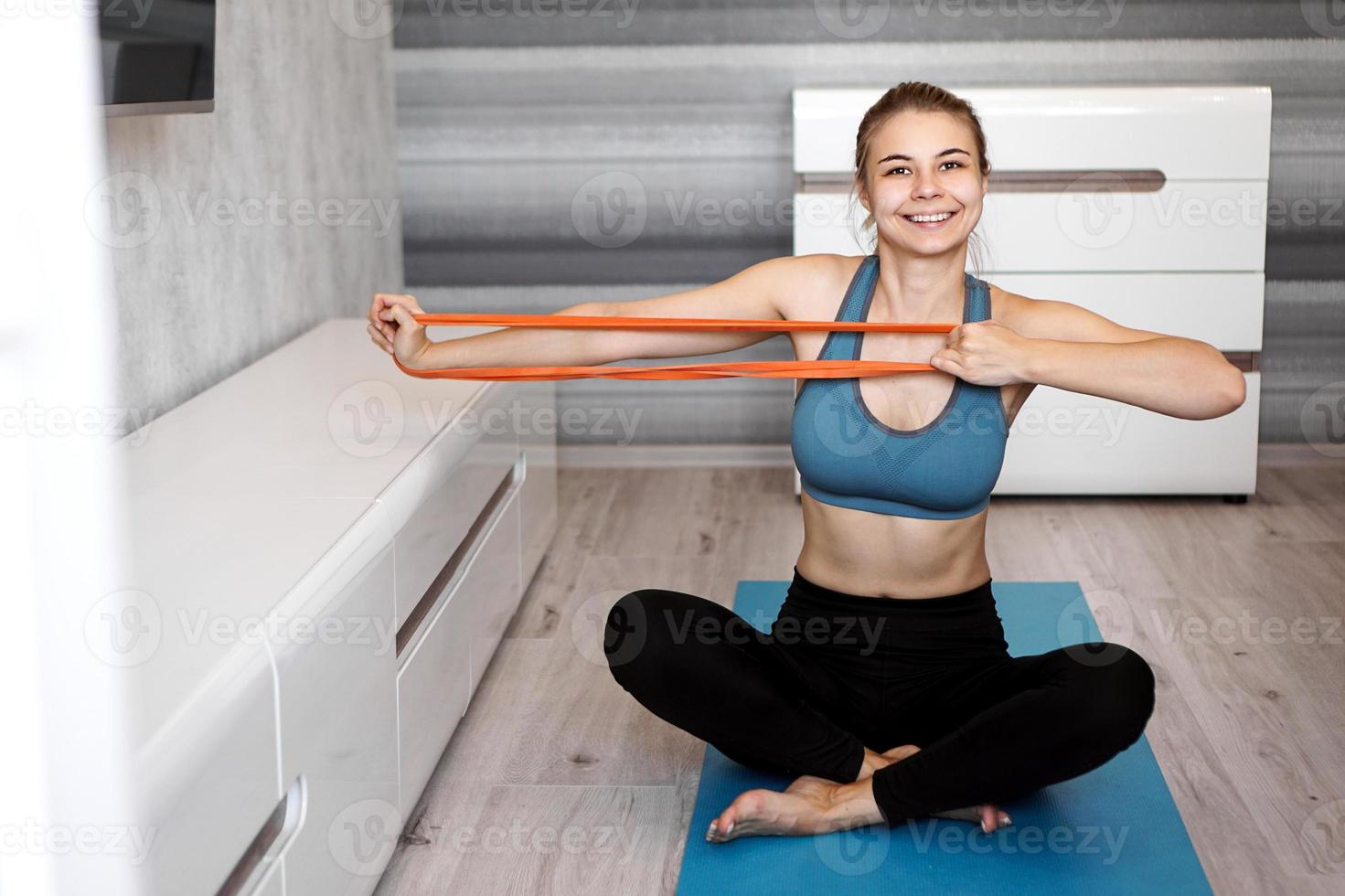 Mujer en casa tratando de perder peso y entrenamiento con banda elástica foto