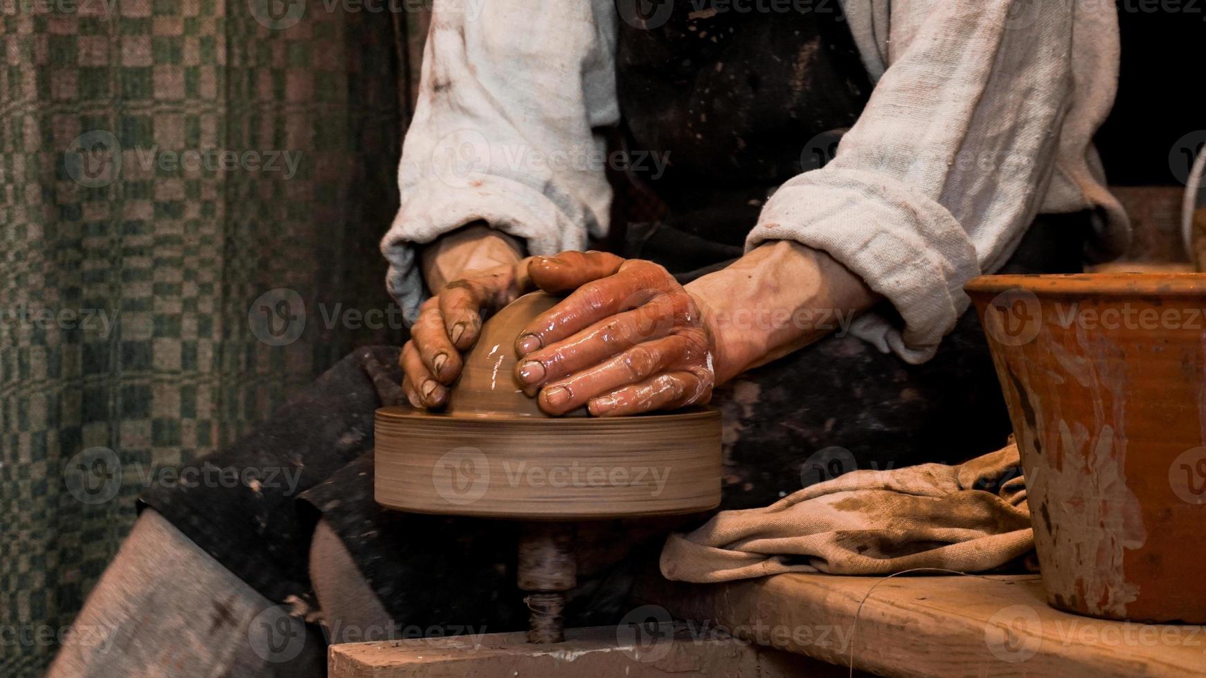 Potter hands making in clay on pottery wheel photo