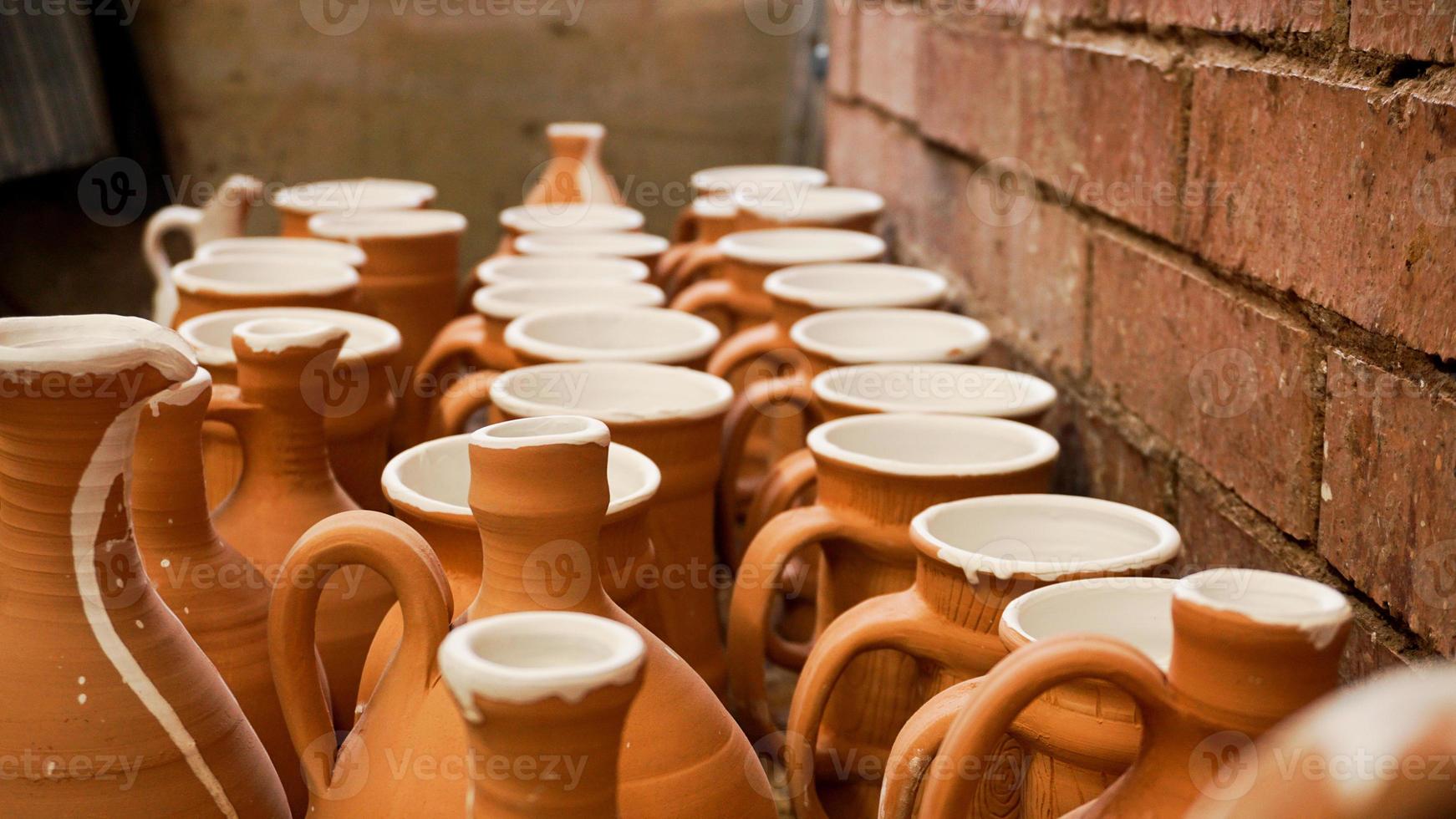 Close-up photo of clay jugs. Rows of handmade earthenware jugs