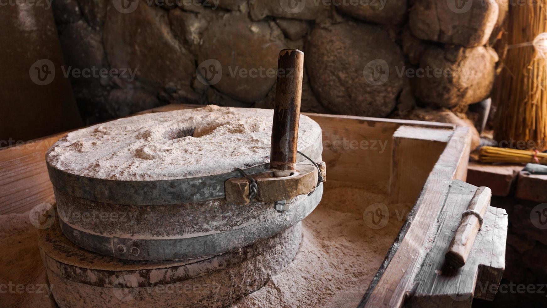 An ancient hand mill made of stones and wood. Flour grinding device photo