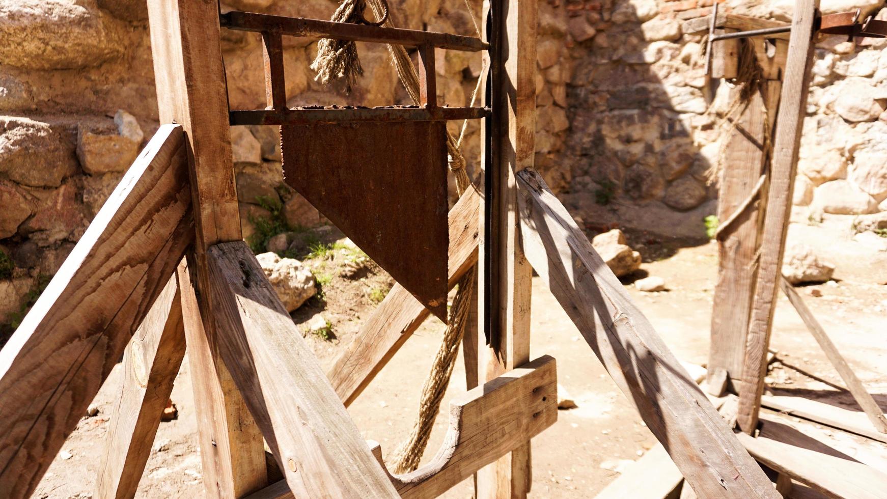 An old guillotine made of wooden planks and an iron blade photo