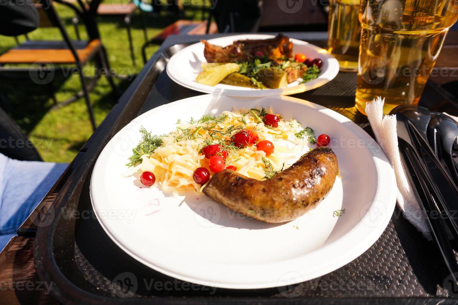 salchicha con ensalada en un plato y cerveza ligera en una bandeja. comida de la calle foto