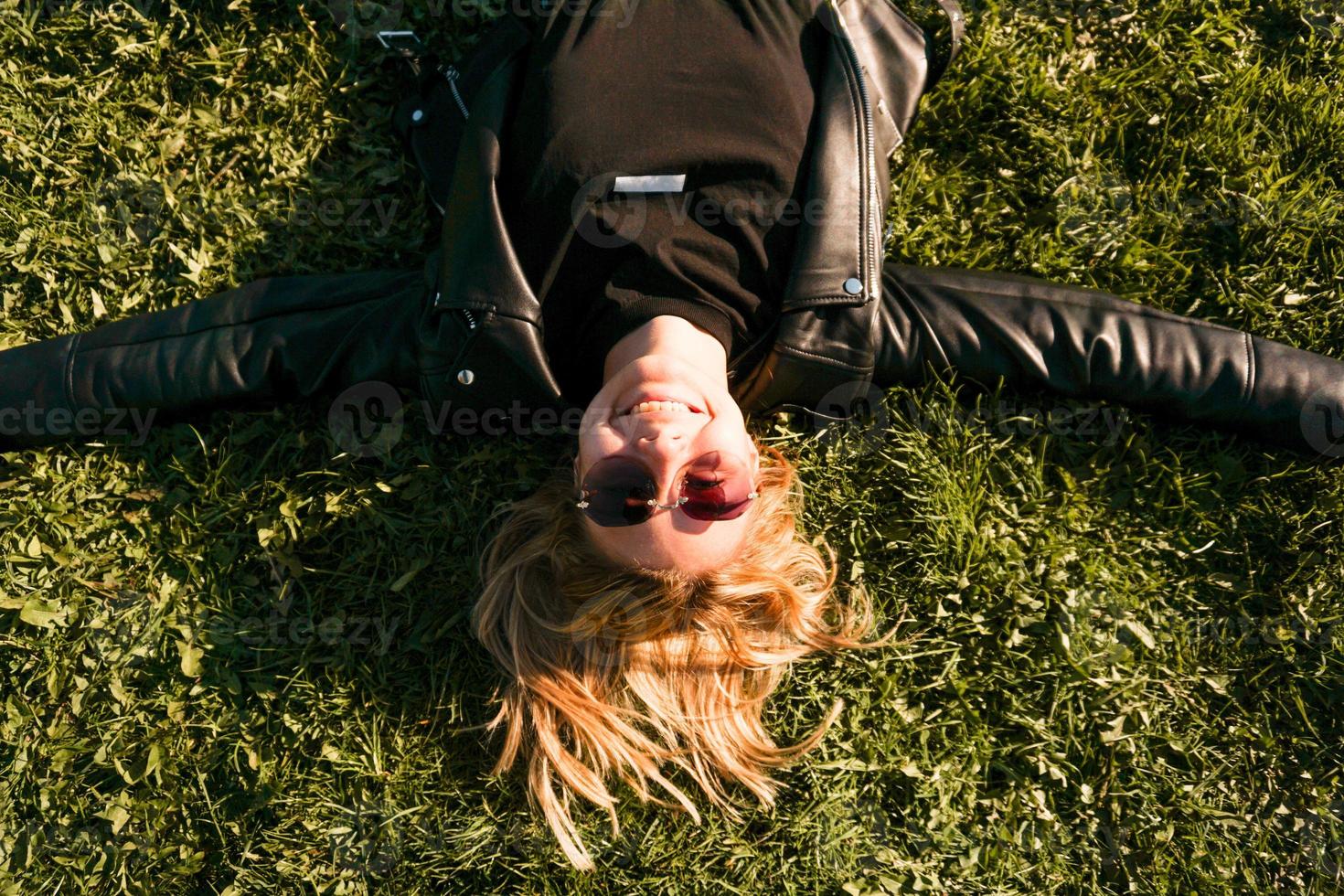 Hermosa joven sana acostada y relajándose sobre la hierba verde foto