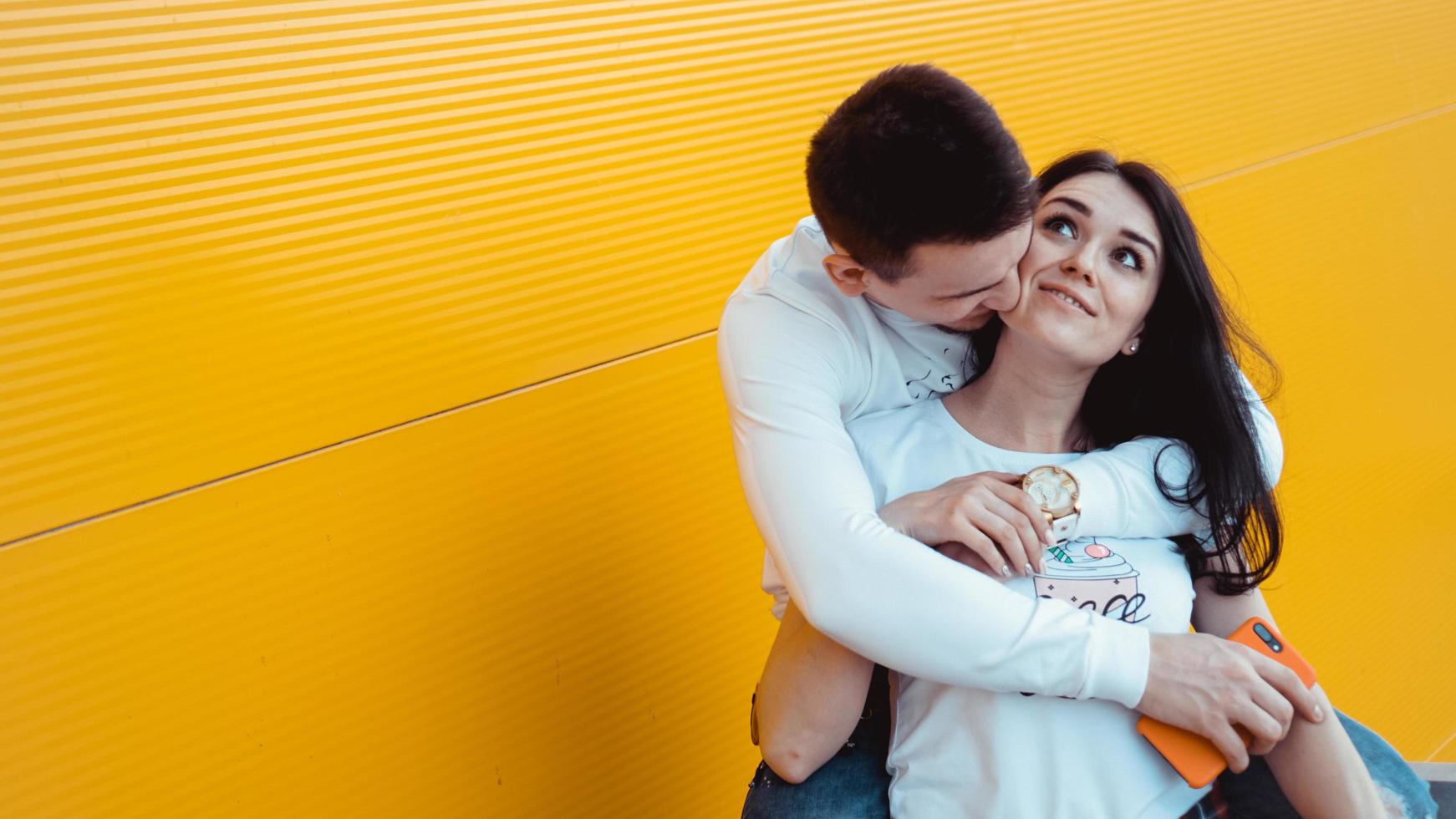 Encantadora pareja joven posando juntos y abrazándose sobre fondo amarillo foto