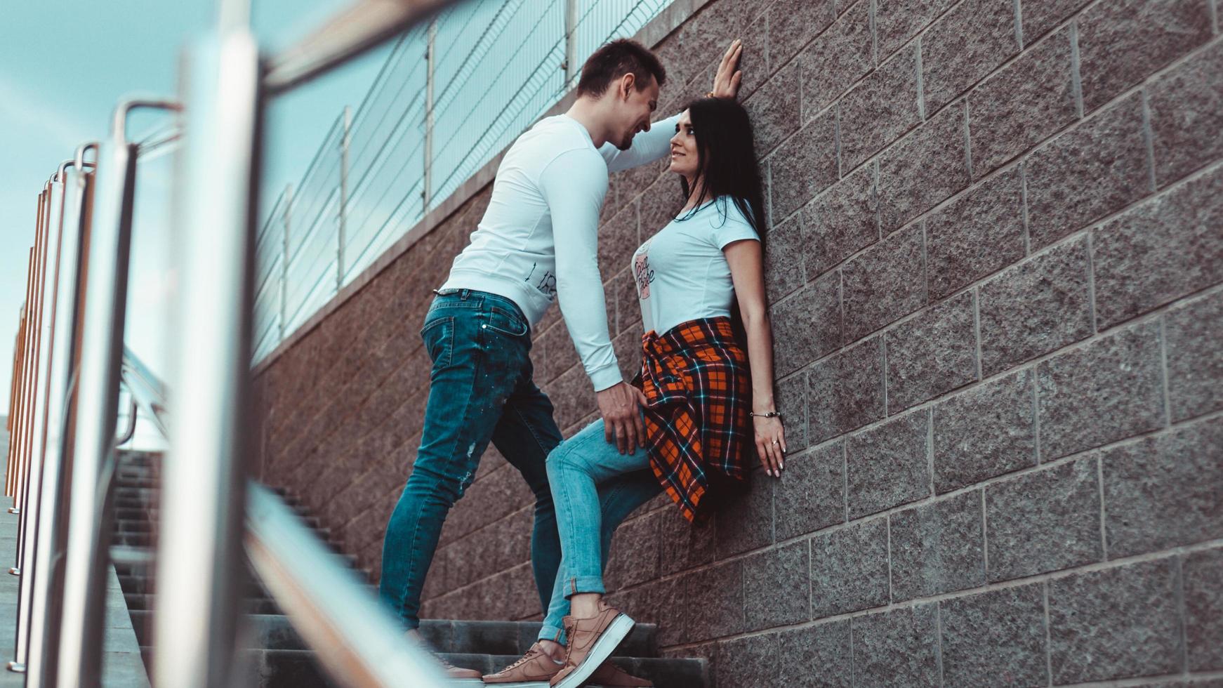 jóvenes parejas amorosas de pie junto a la pared de ladrillo foto