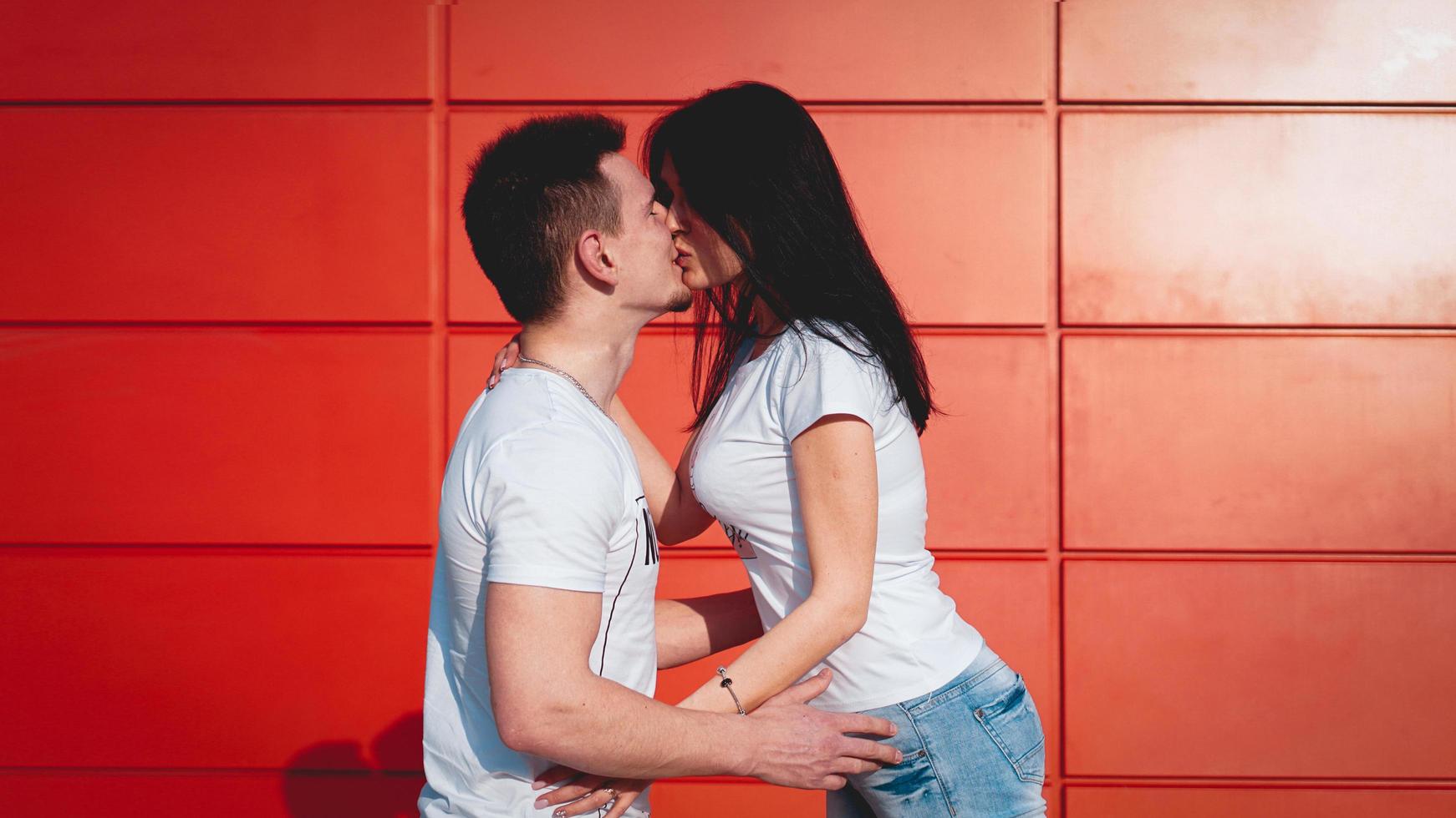 Couple kissing against isolated red wall in the city photo