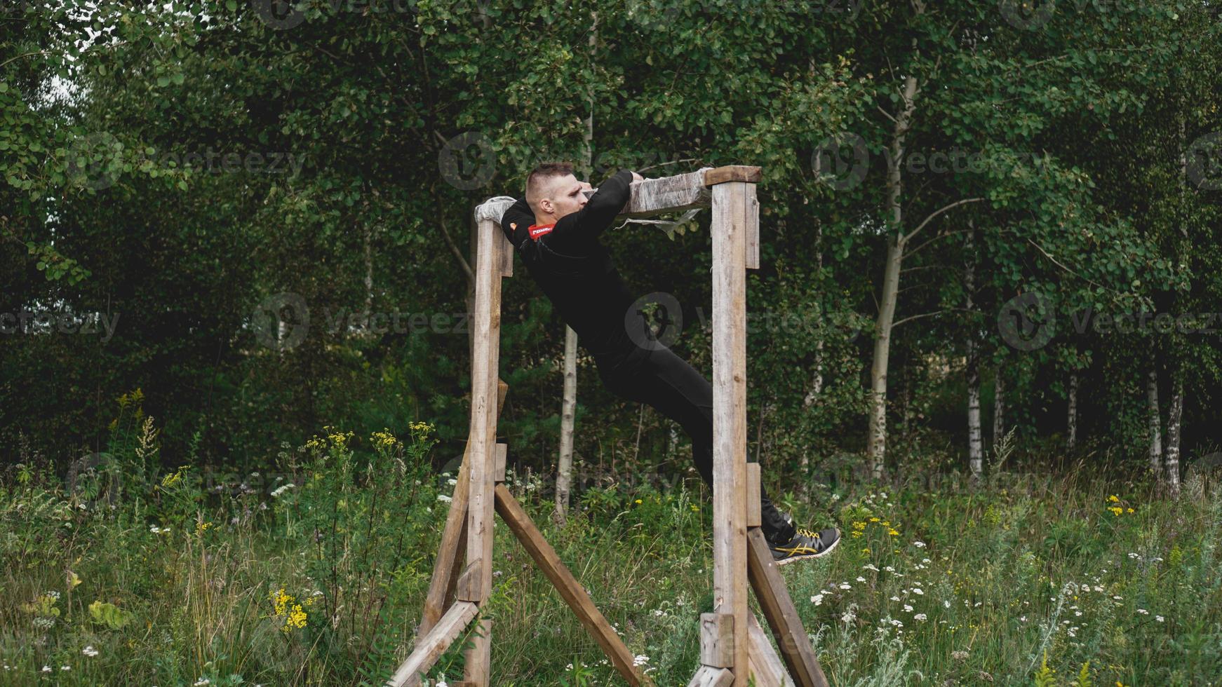 El hombre atravesando obstáculos durante la carrera de obstáculos en el campo de entrenamiento foto