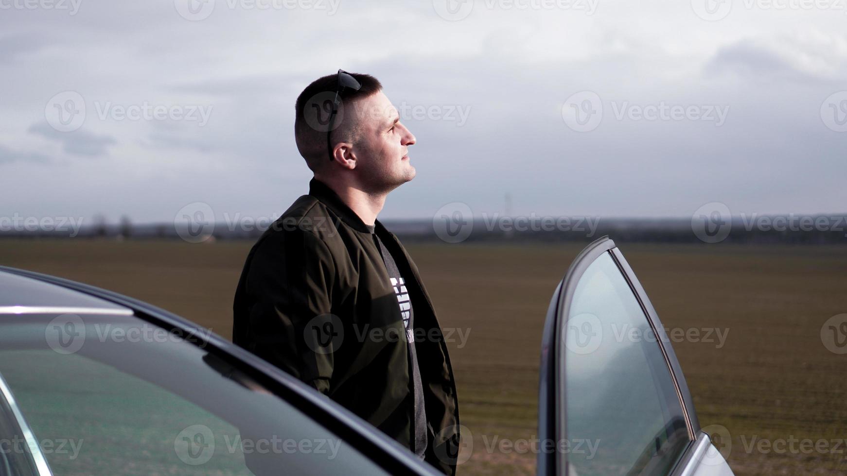 hombre guapo de pie cerca de su coche nuevo foto