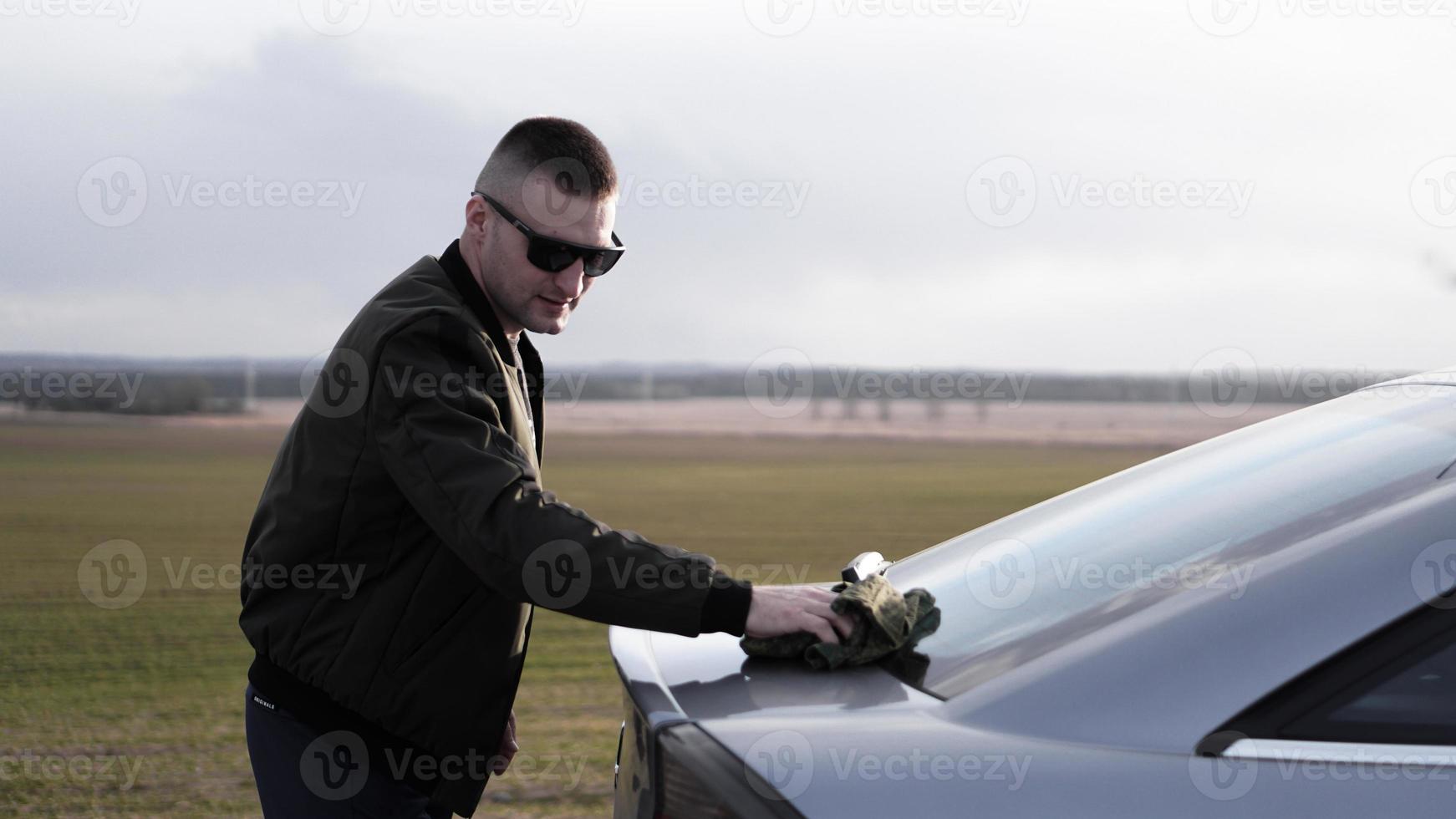 Shot of young man polishing his car with a cloth photo