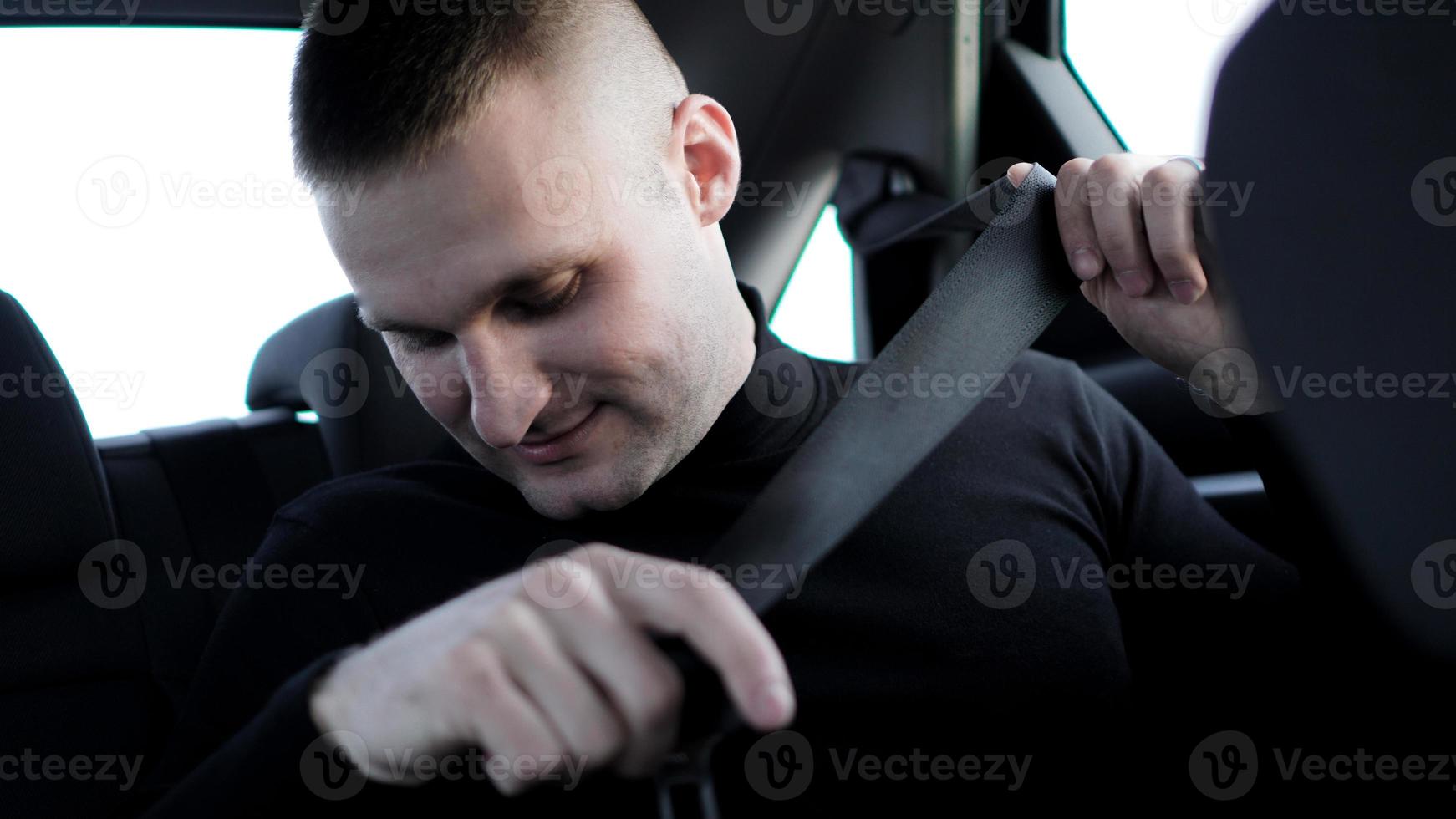 Businessman in his car fastening the seatbelt, safe driving concept photo