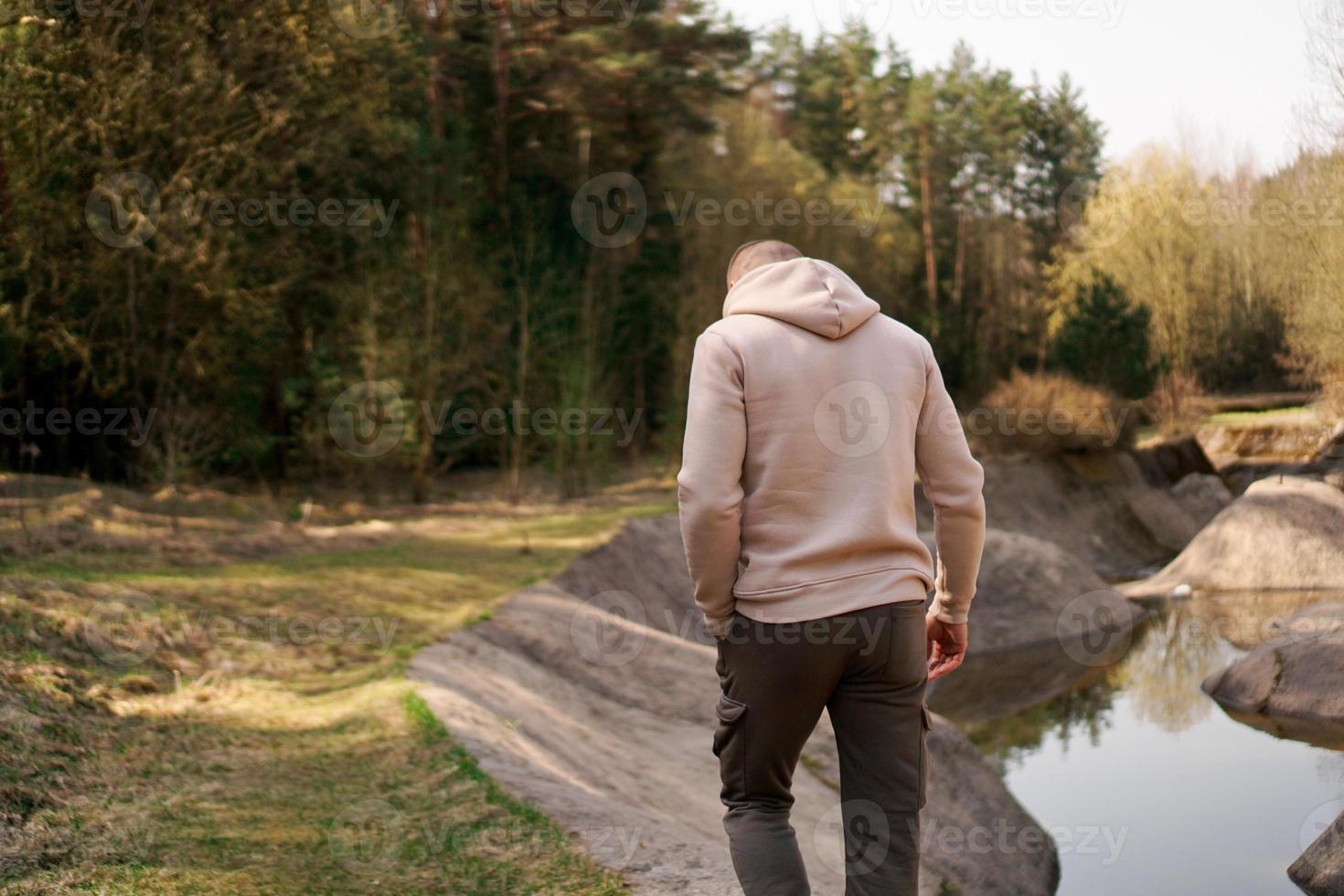 Un hombre camina por el bosque junto a un canal de remo o un río de montaña. foto