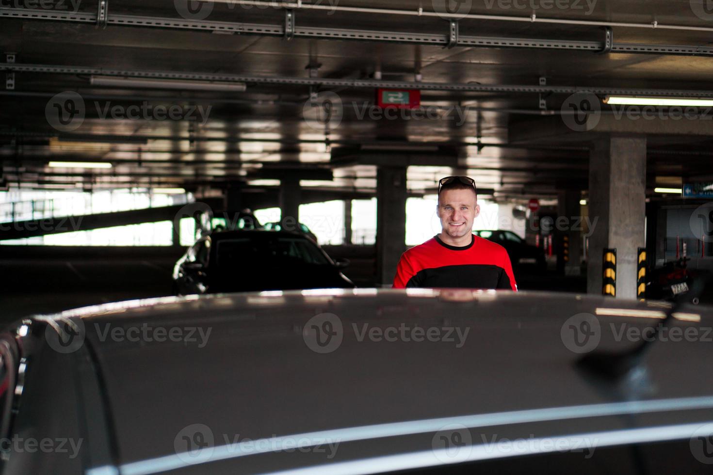 A young man in a tracksuit stands next to a car photo