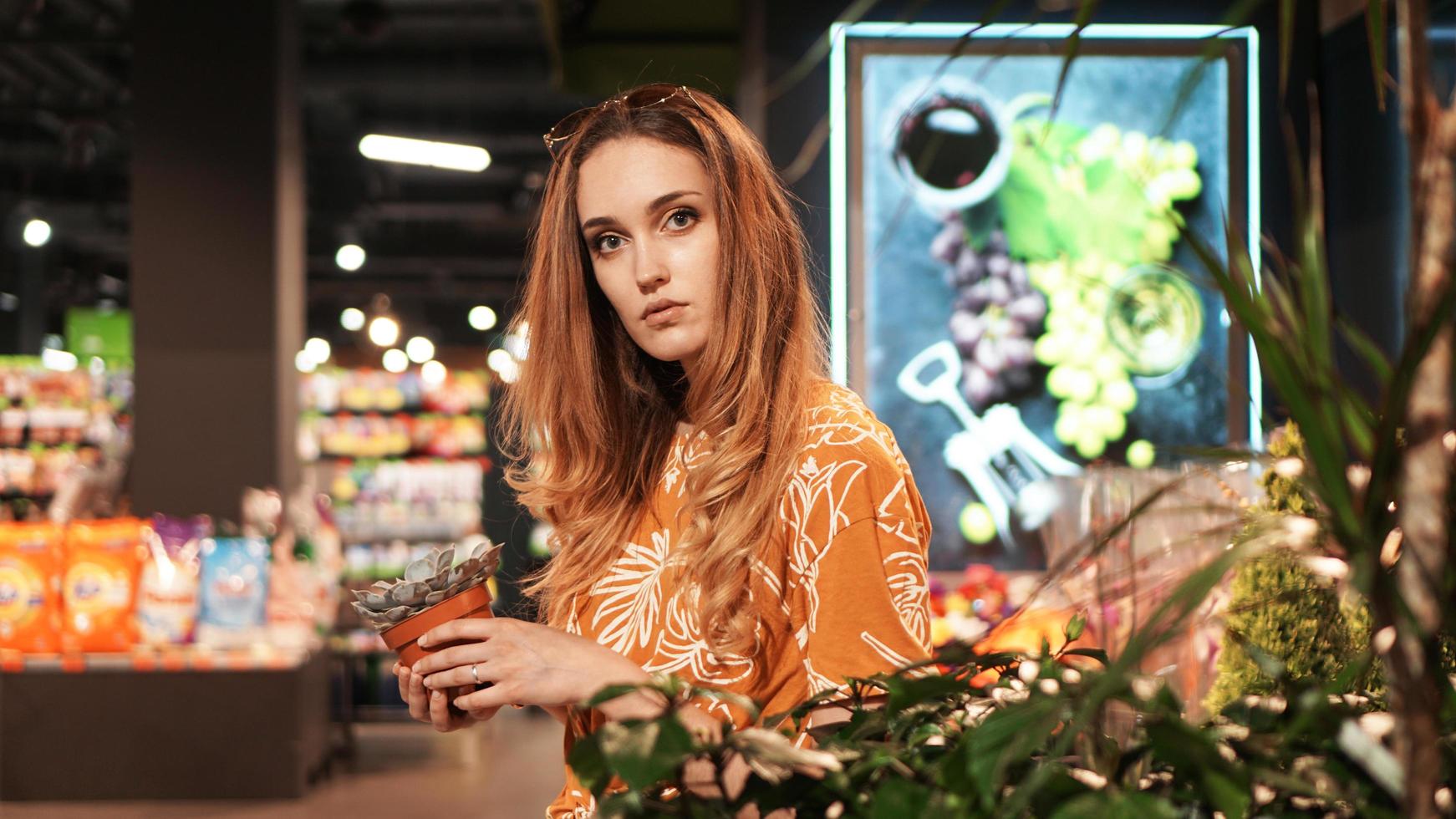 Mujer joven comprando flores en un centro de jardinería foto