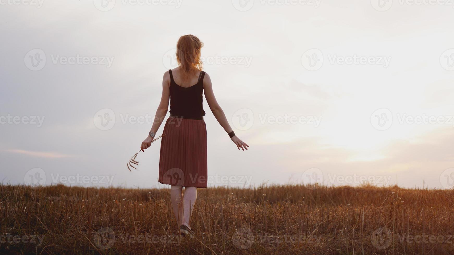 Young woman enjoying nature and sunlight in straw field photo