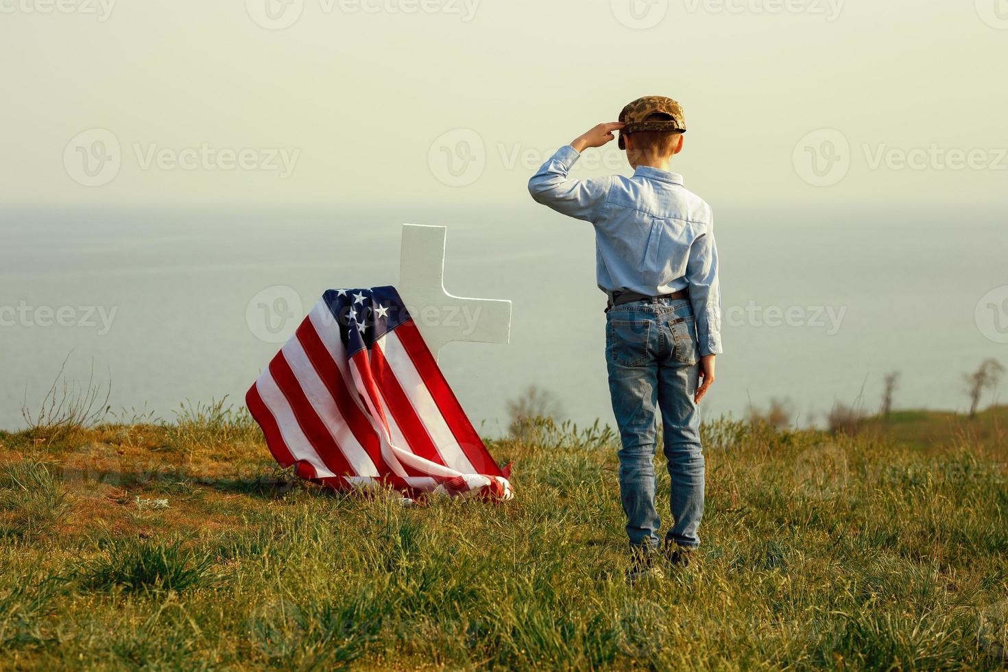 Young boy in a military cap salutes his father's grave photo
