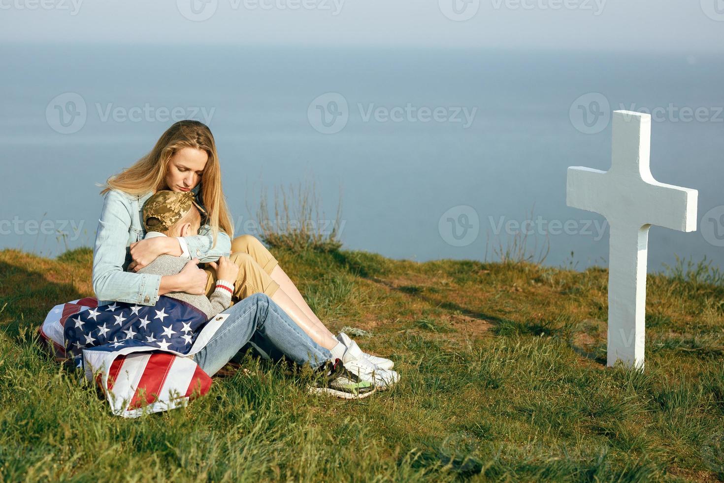 Mom and son are sitting on the grave of a soldier photo