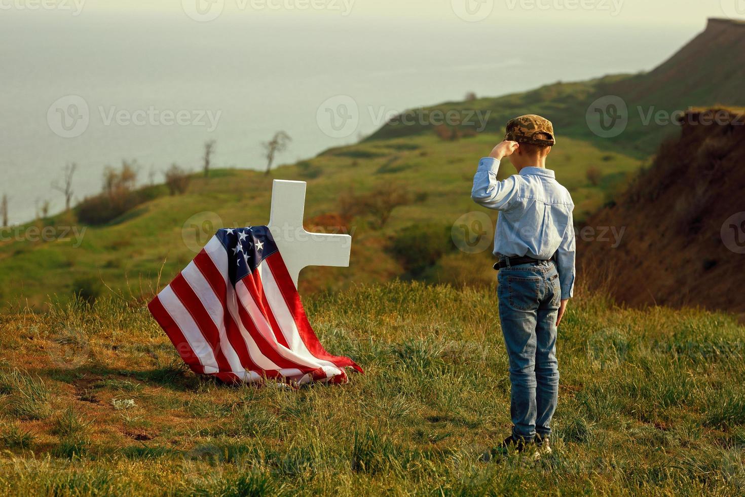 Young boy in a military cap salutes his father's grave photo