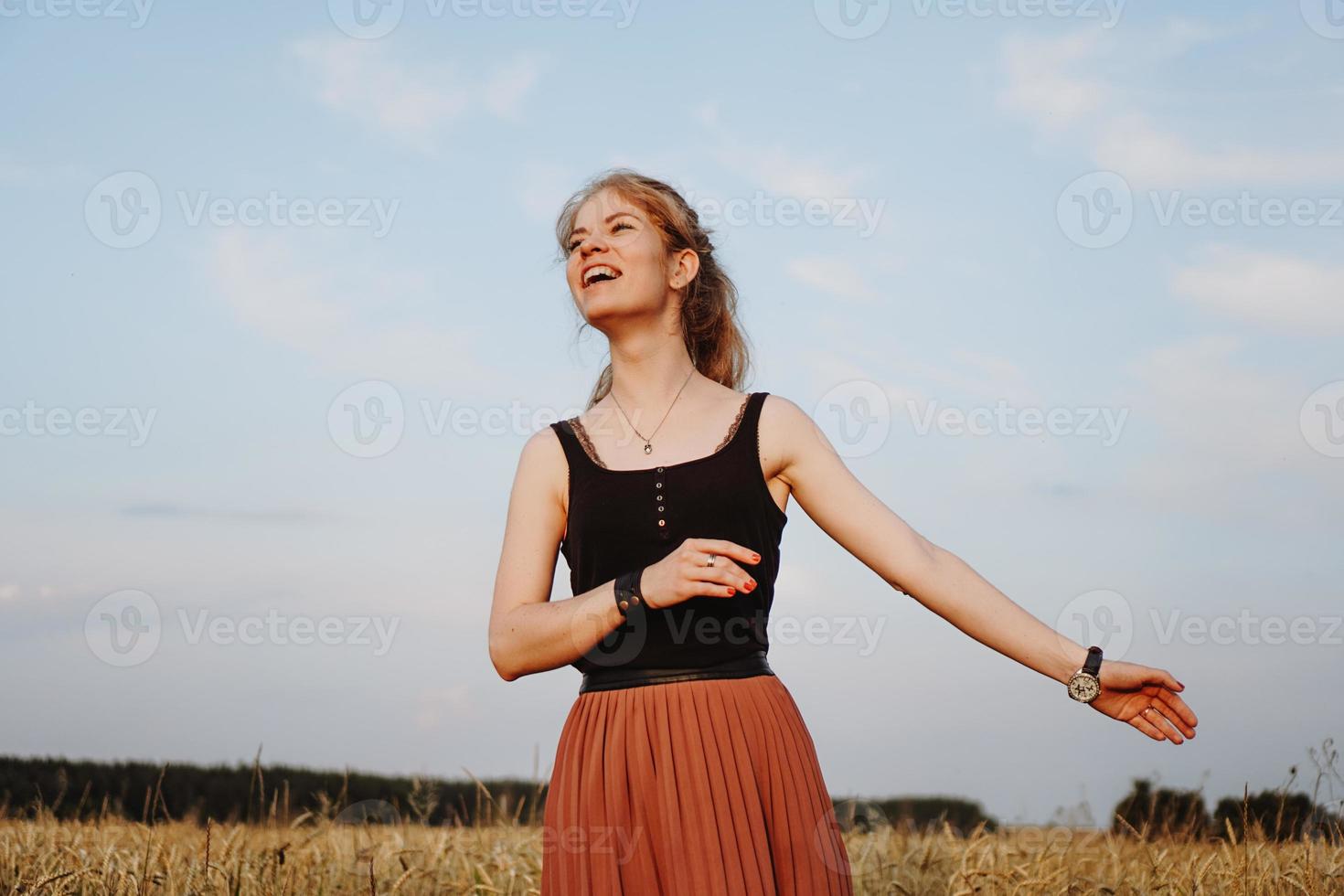 Mujer joven disfrutando de la naturaleza y la luz del sol en el campo de paja foto