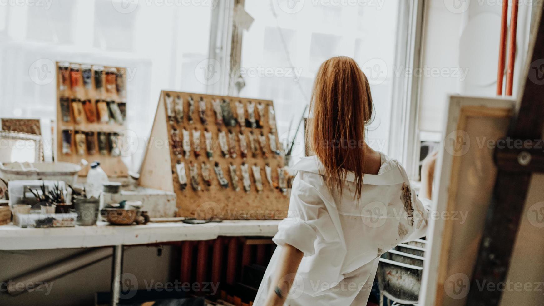 Beautiful female painter dancing while painting in art workshop photo