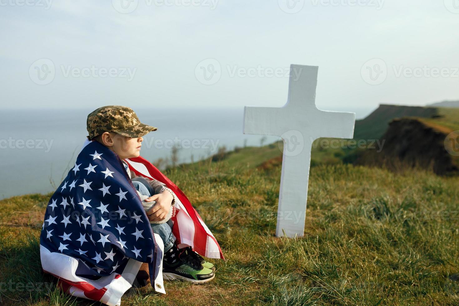 Joven con una gorra militar en la tumba de su padre en el día de los caídos foto