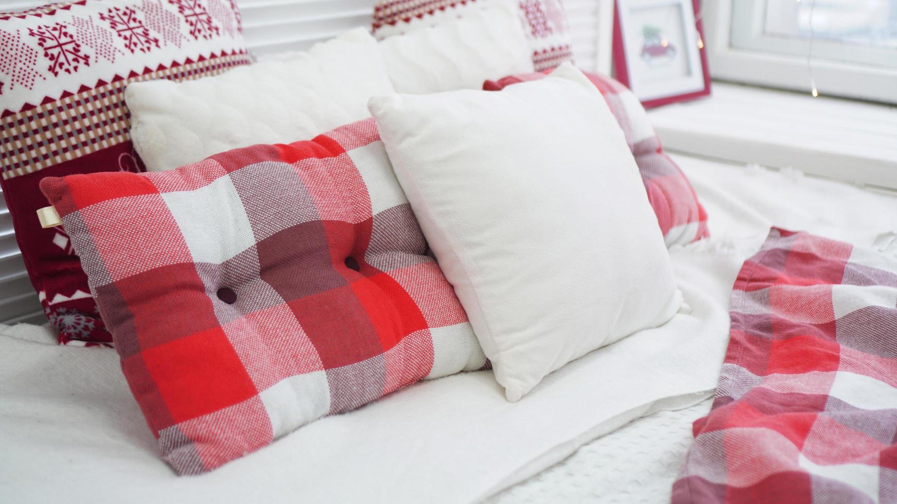 decoraciones navideñas de invierno. almohadas rojas blancas en la cama foto