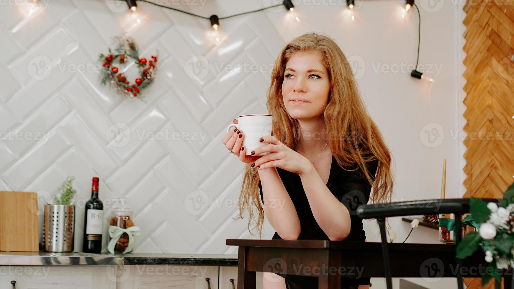 Mujer sostiene una taza de café por la mañana en la cocina de Navidad foto